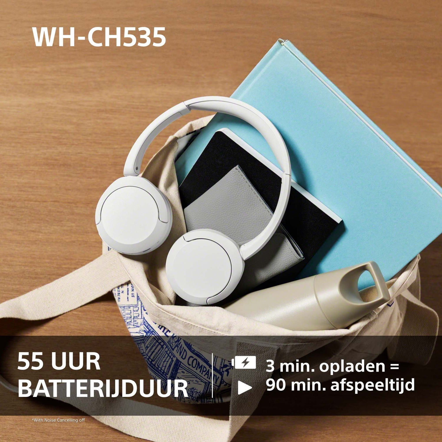Witte koptelefoon, blauw boek, grijze notitieboekjes en fles in een stoffen tas op hout.
