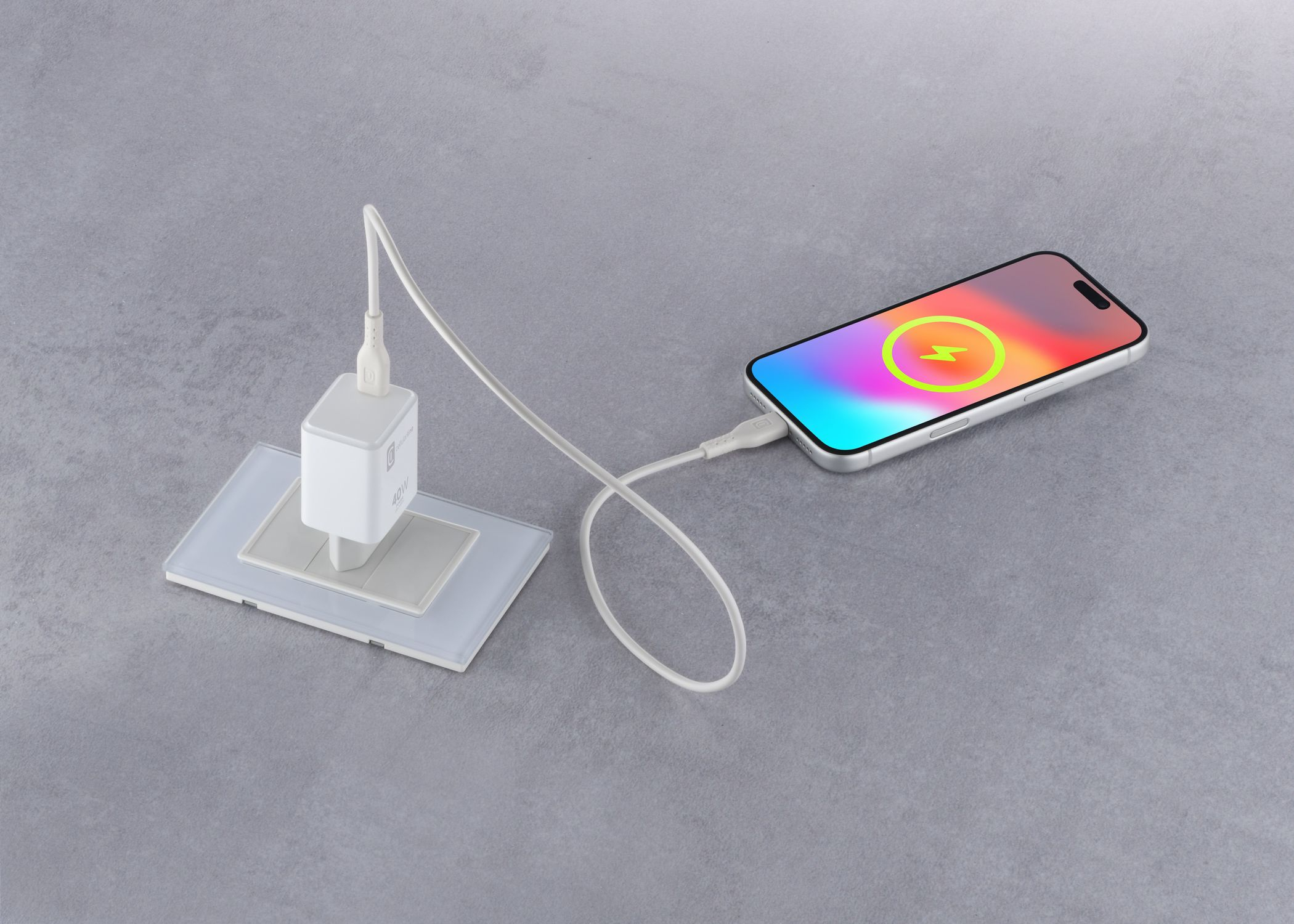 Un teléfono se carga mediante un cable USB-C blanco y un adaptador en un enchufe gris.