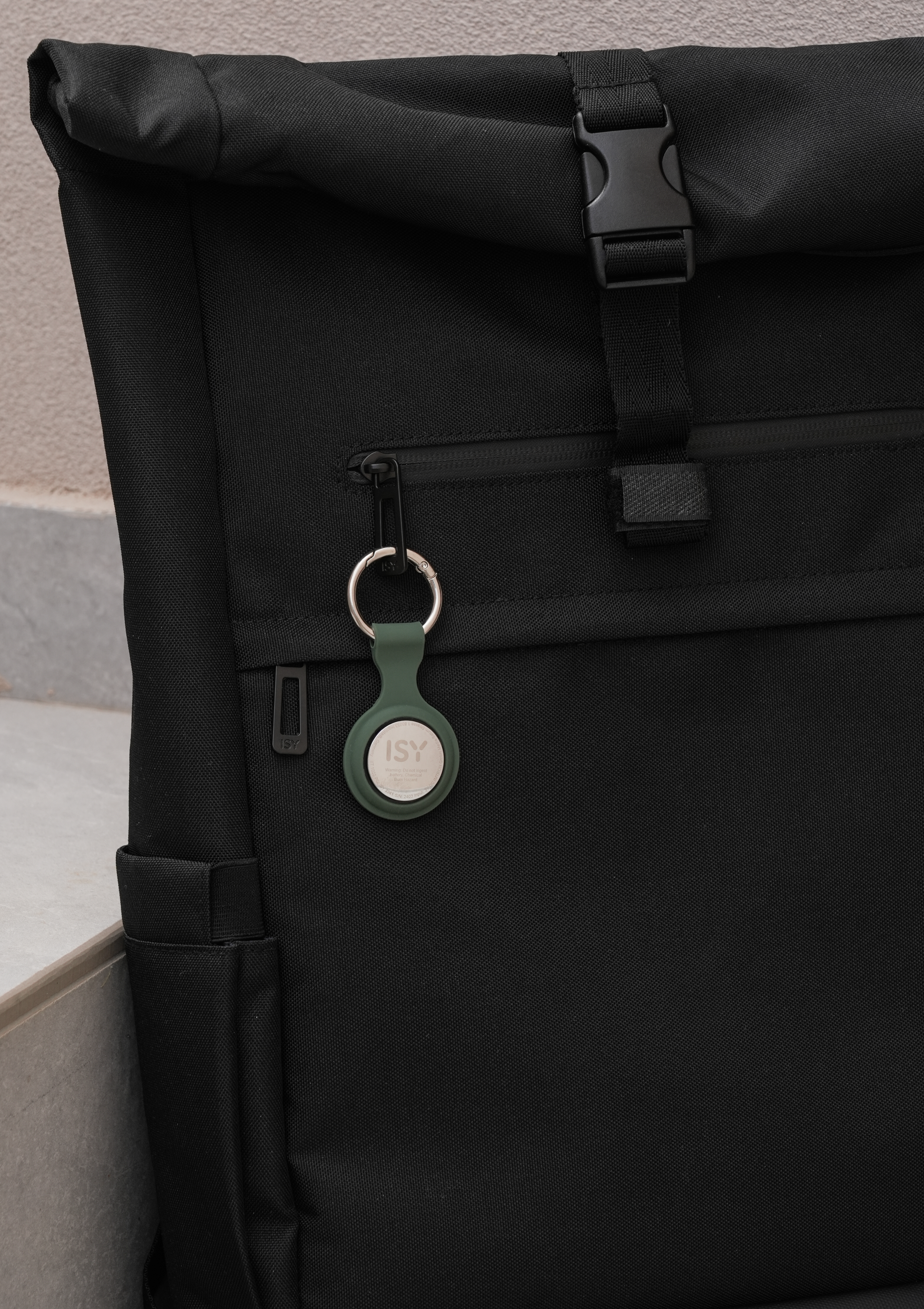 Un sac à dos noir avec un traceur vert attaché à la fermeture éclair.