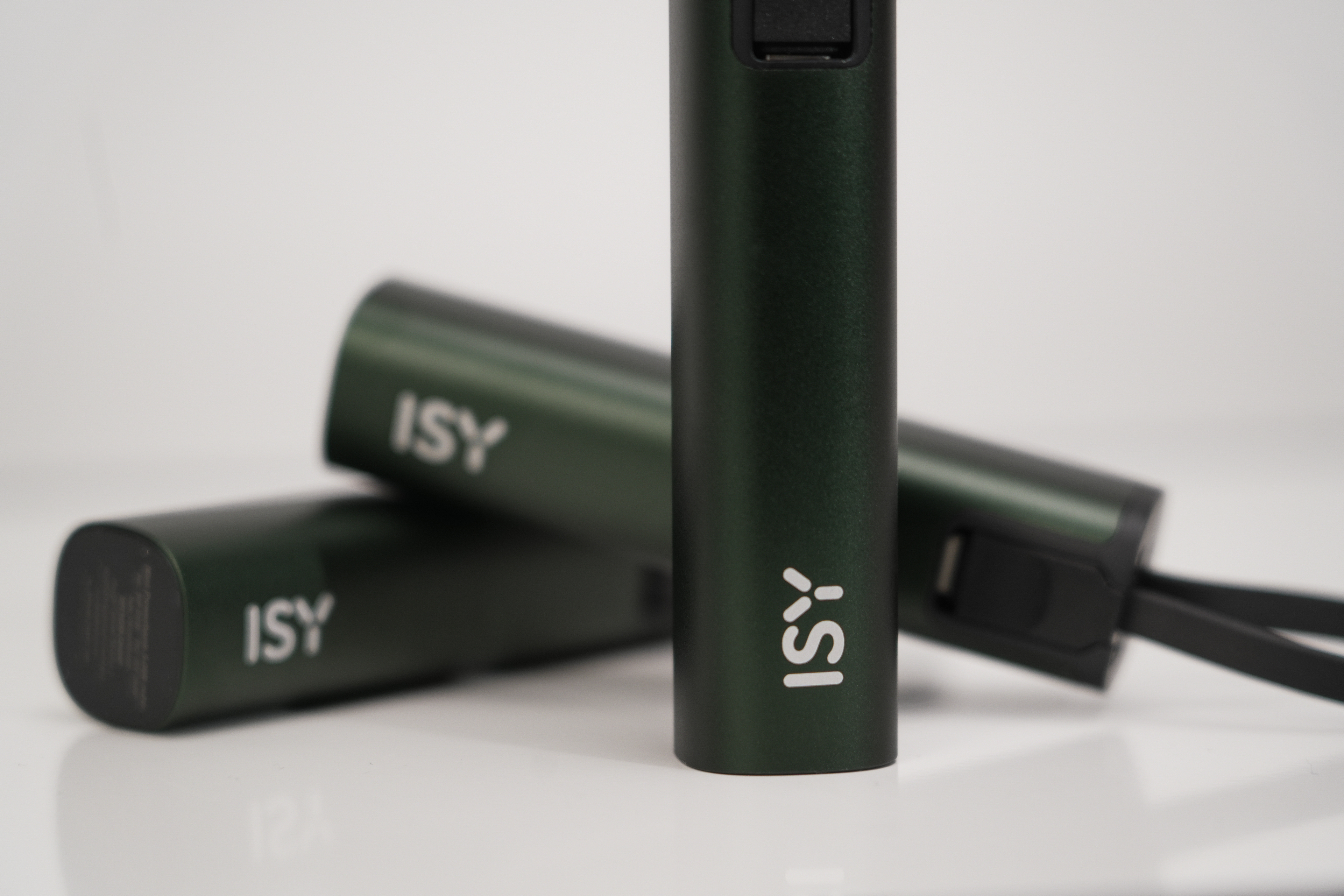 Trois batteries externes ISY vertes sur fond blanc, une au premier plan.