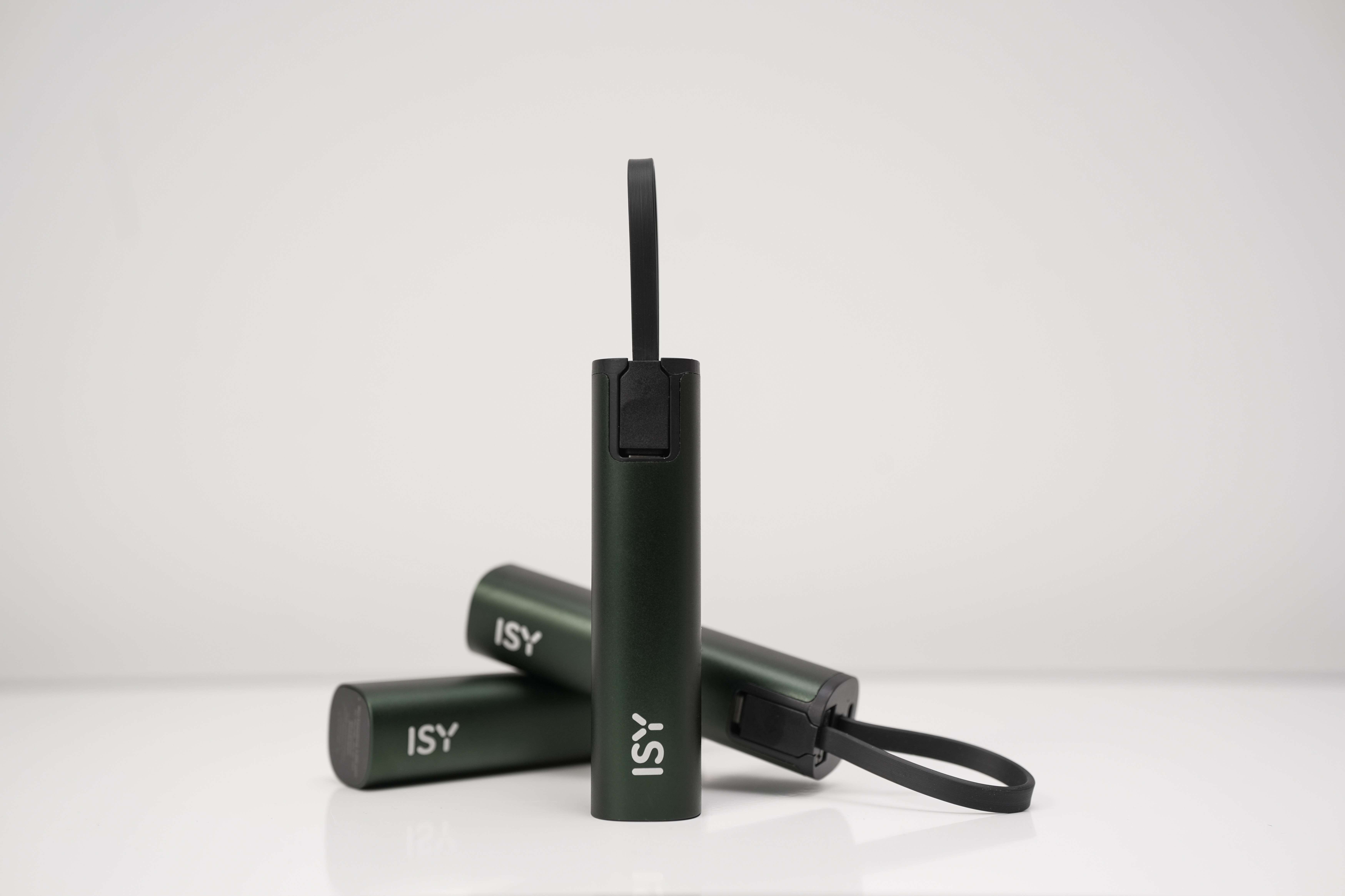 Trois batteries externes ISY vertes avec dragonnes noires sur une surface blanche et fond neutre.