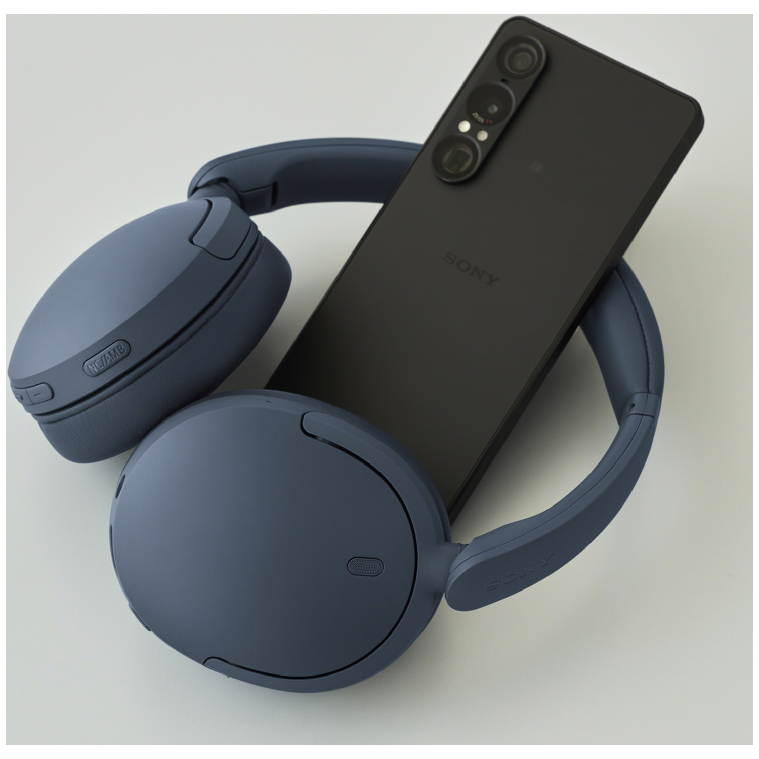 Casque supra-auriculaire bleu et smartphone noir sur fond clair.