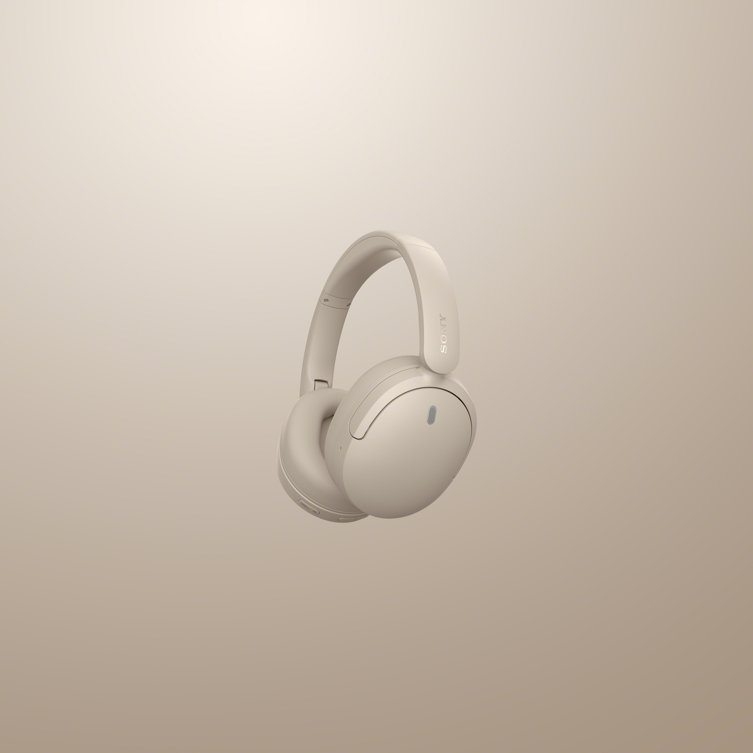 Un casque audio beige flotte sur un fond beige assorti.