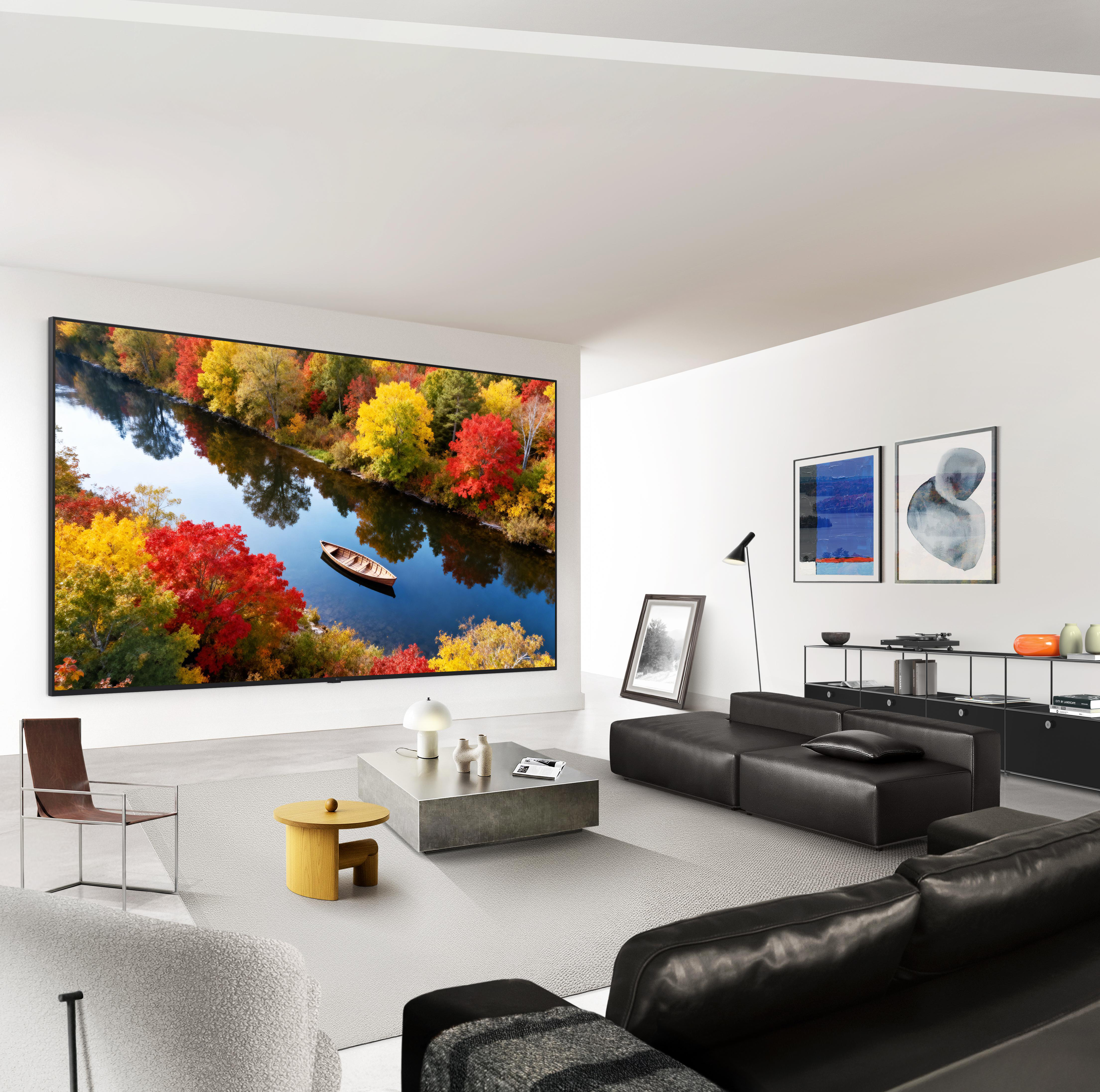 Modernes Wohnzimmer mit riesigem Herbstwald-Wandbild, schwarzen Sofas, Beistelltischen und Kunst an der weißen Wand.