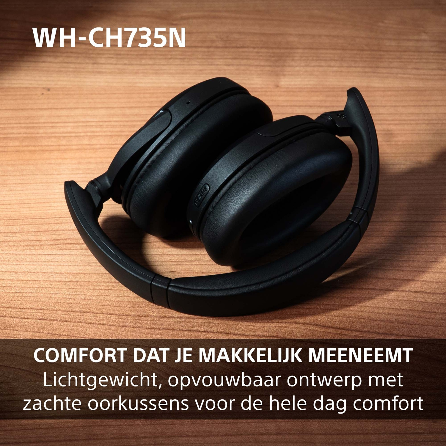 Zwarte opvouwbare draadloze koptelefoon op een houten tafel met Nederlandse tekst.