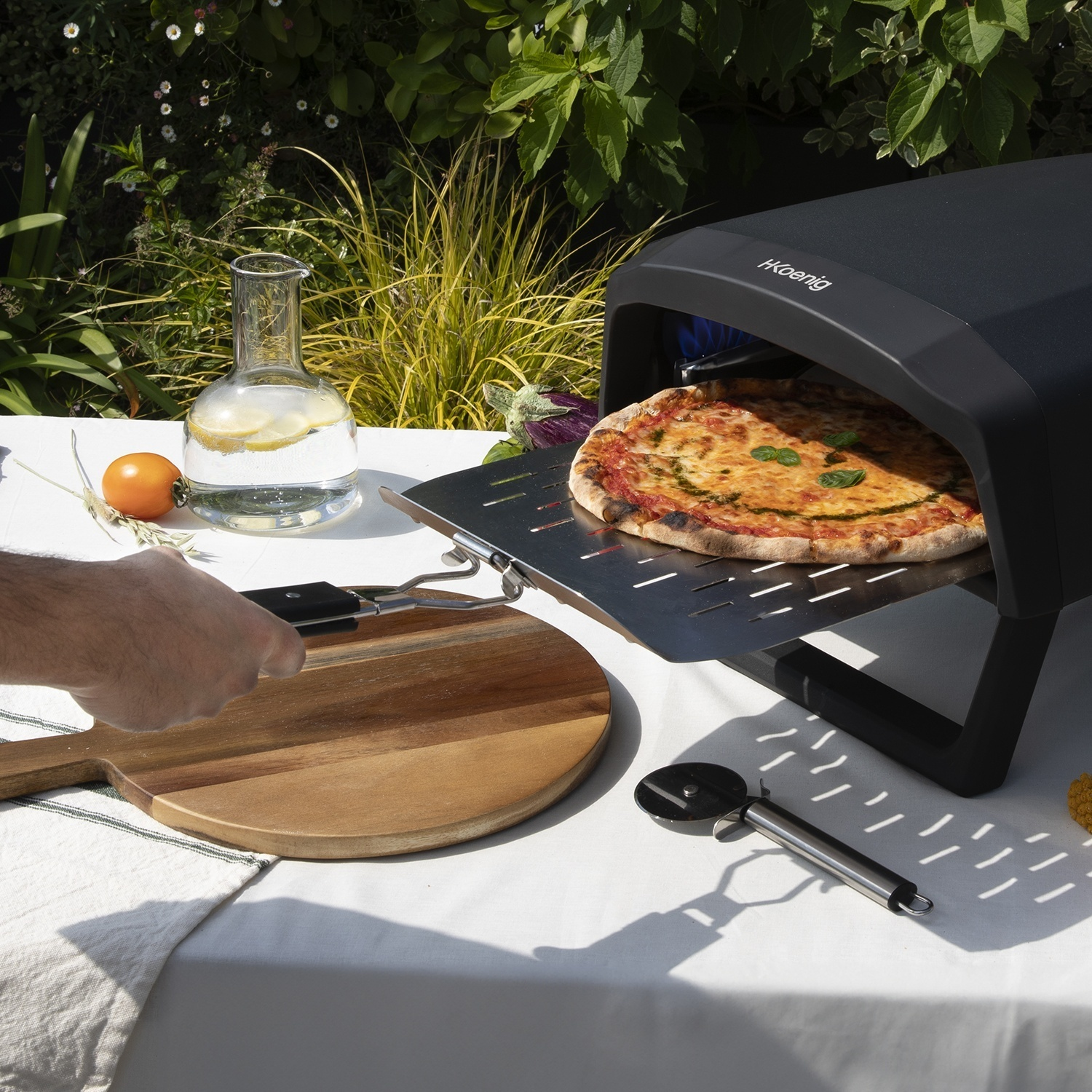 Una persona usa una pala per infornare una pizza in un forno nero su un tavolo.