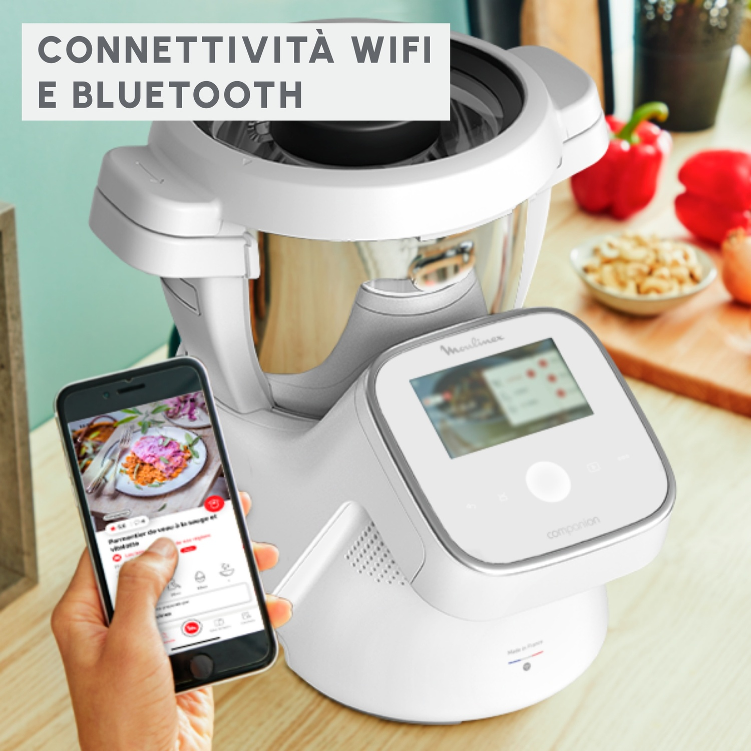 Una mano usa un'app per smartphone davanti a un robot da cucina bianco Moulinex.