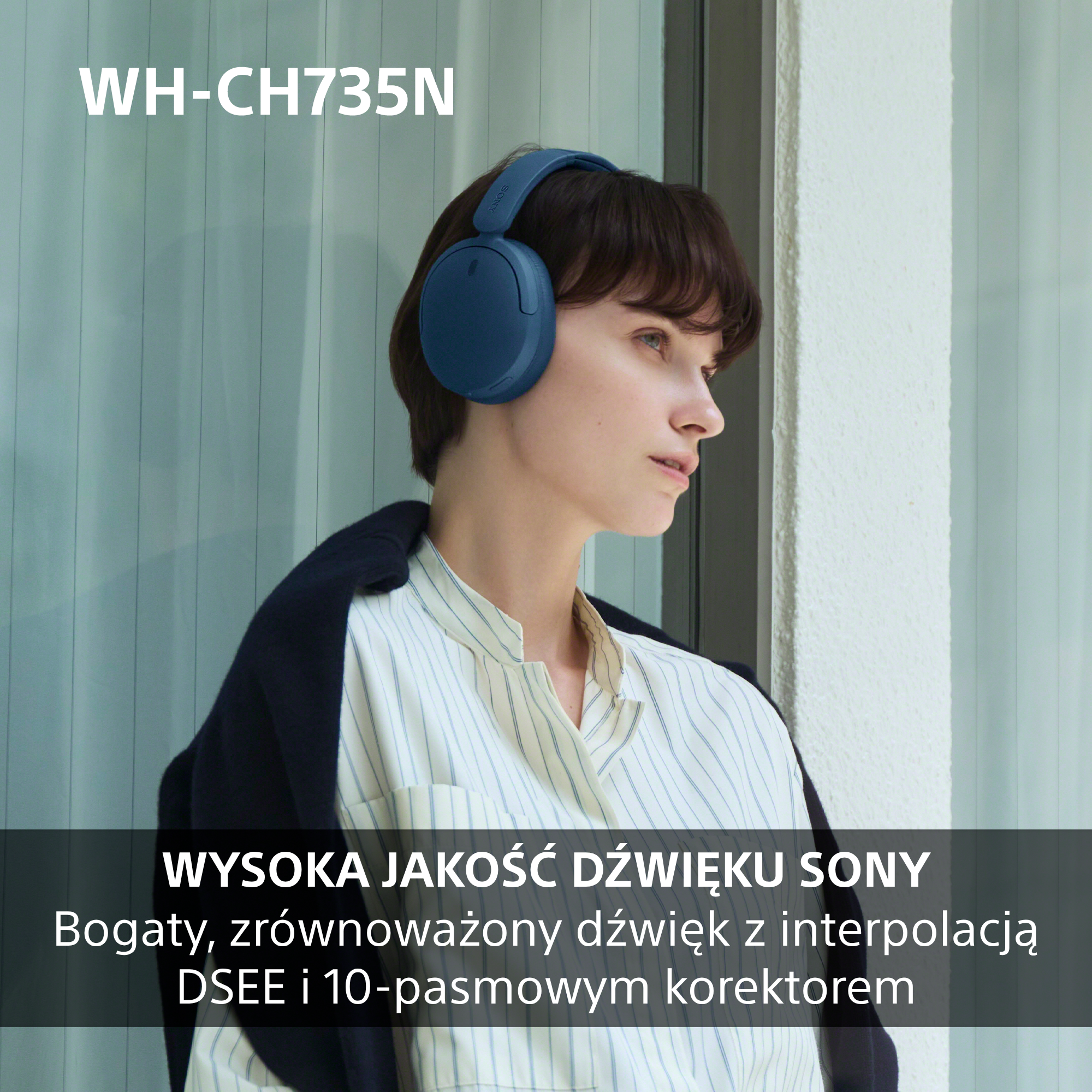 Kobieta w niebieskich słuchawkach stoi przed jasnym oknem.