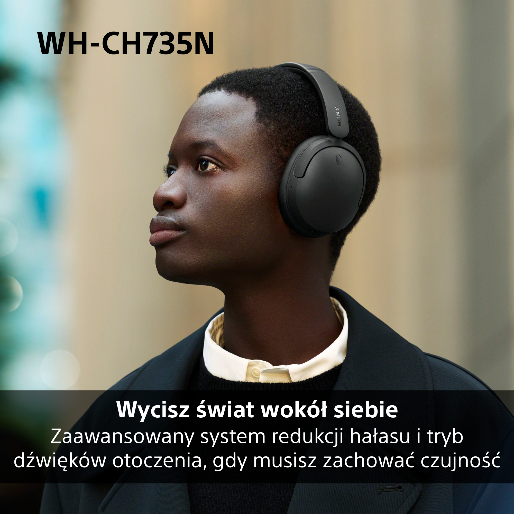 Młody mężczyzna w czarnych słuchawkach patrzy z zamyśleniem w bok na rozmytym tle.