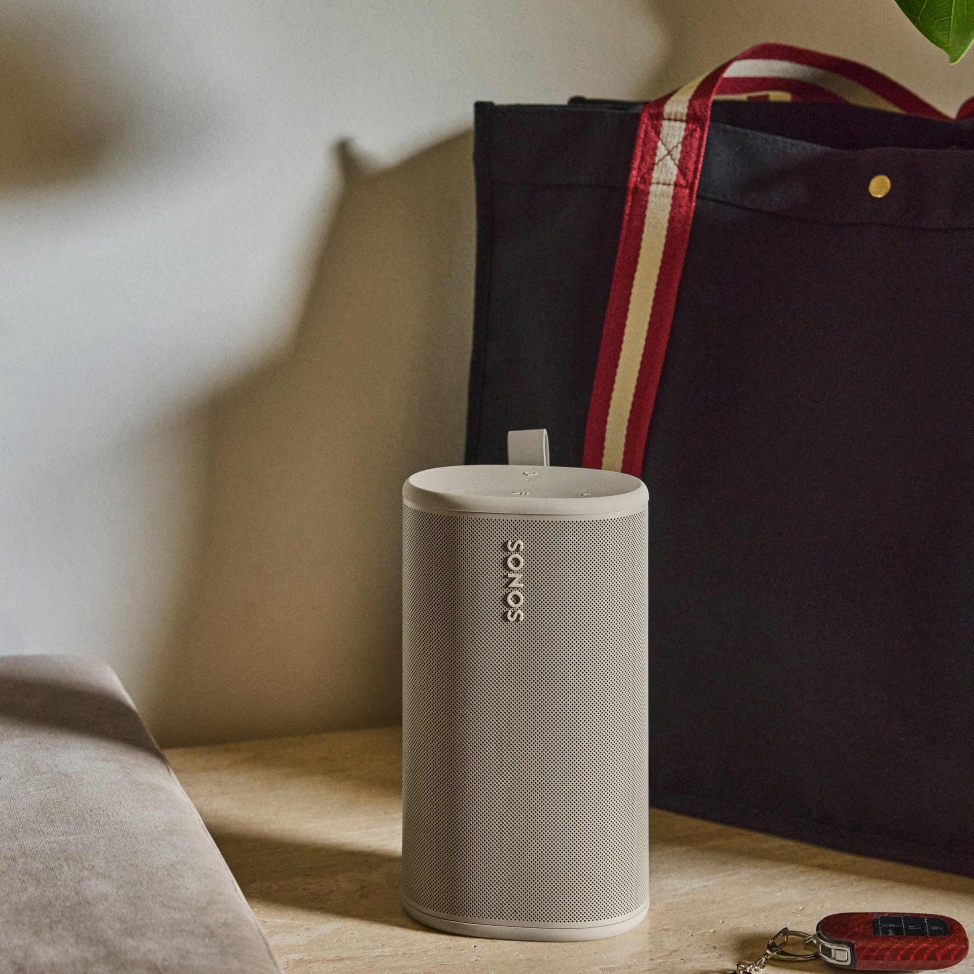 Une enceinte Sonos beige est posée sur une table devant un sac noir.