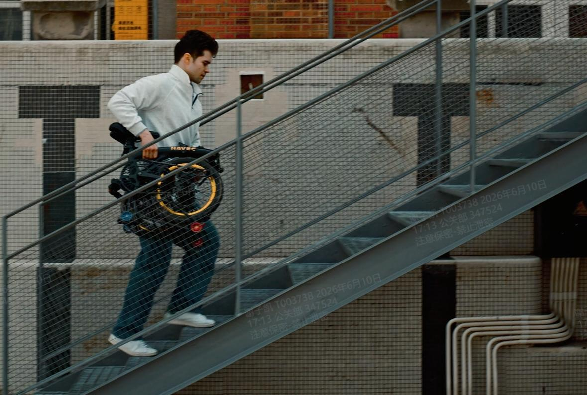 Ein Mann in weißer Jacke trägt ein zusammengeklapptes Fahrrad eine Metalltreppe hinauf.