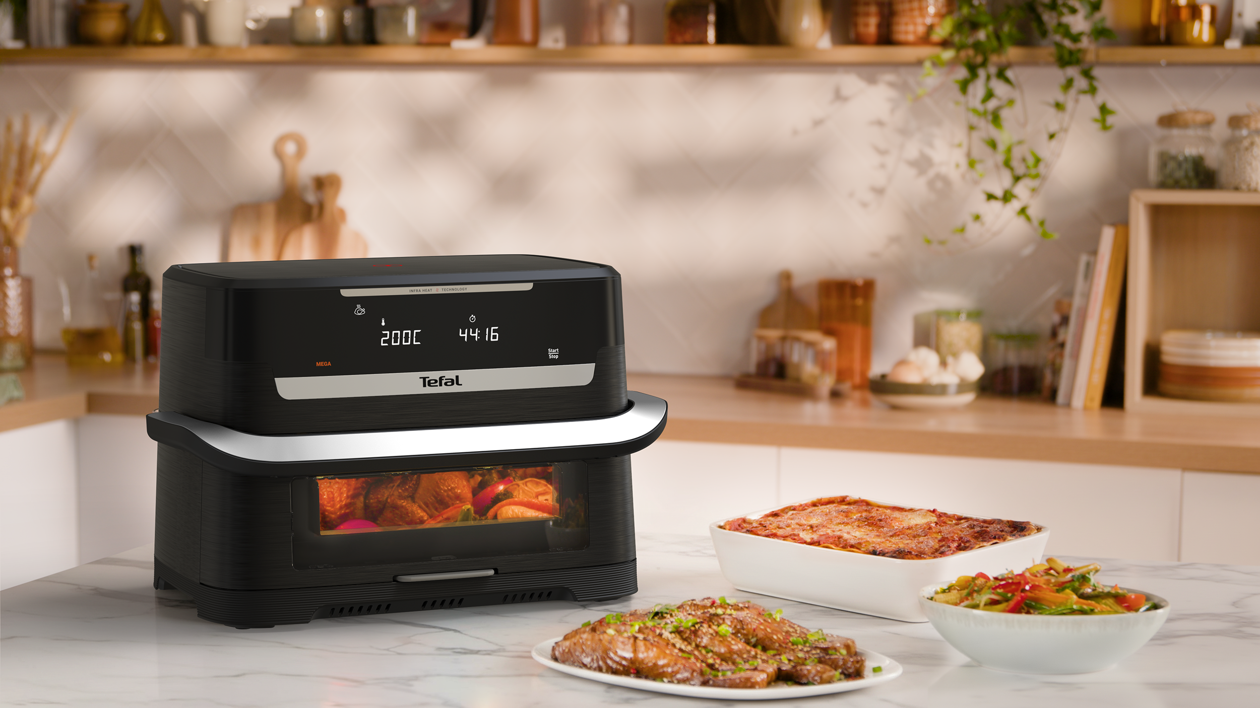 Egy fekete Tefal légkeveréses fritőz konyhapulton, elkészült ételekkel.