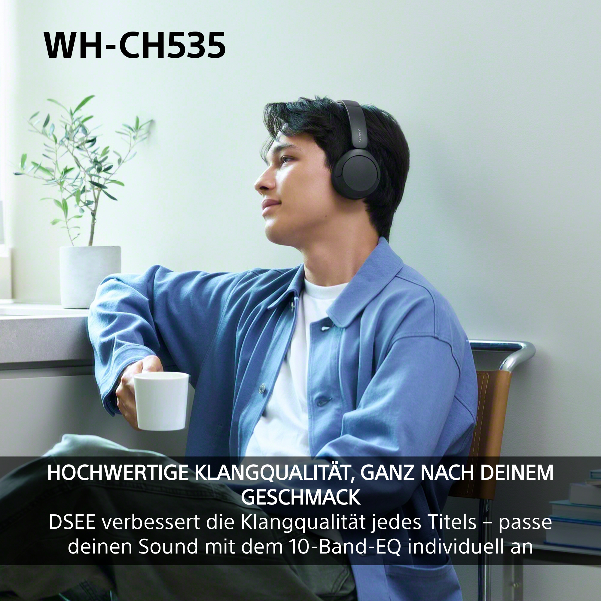 Ein junger Mann mit Kopfhörern sitzt entspannt, hält eine Tasse und schaut nachdenklich aus dem Fenster.