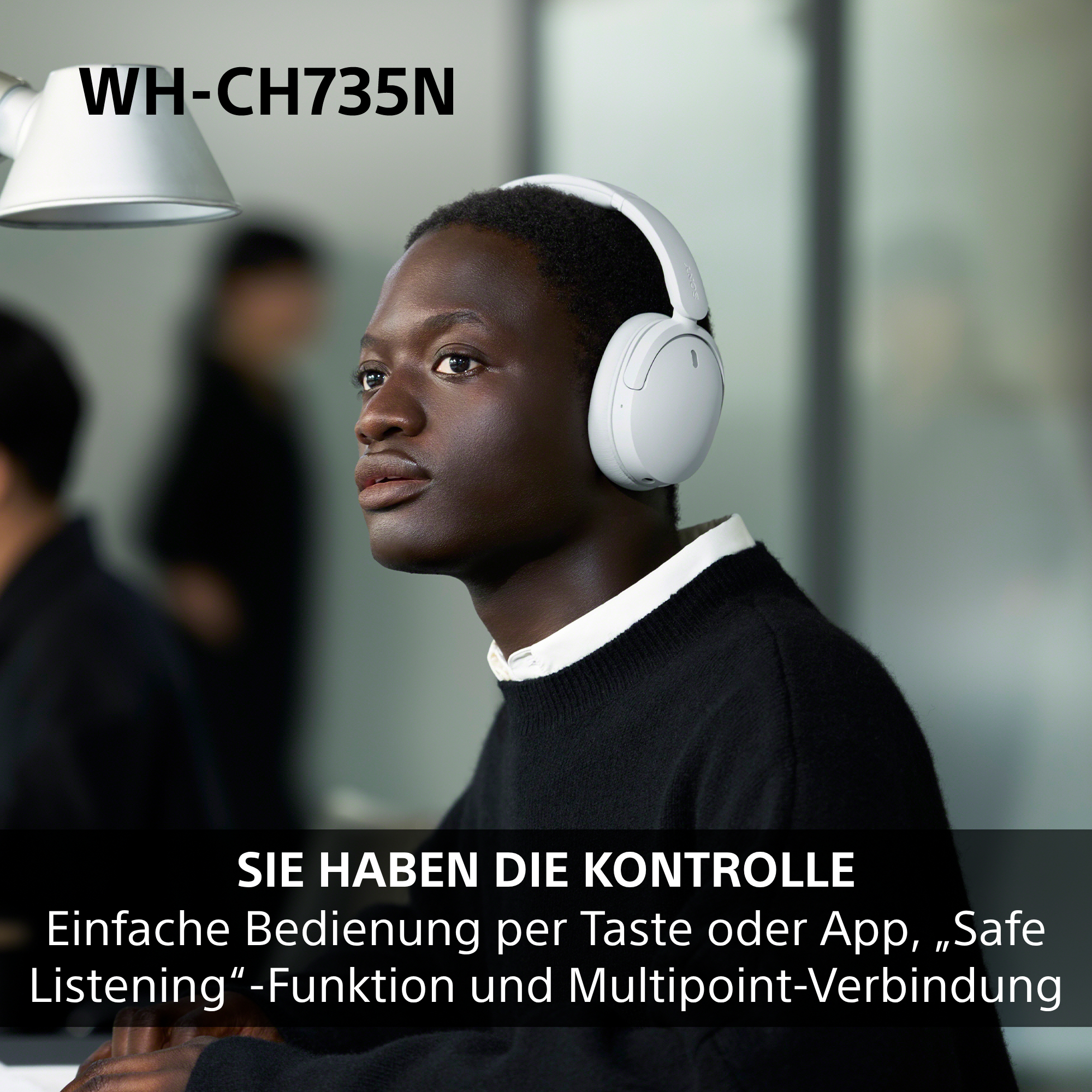 Ein junger Mann trägt weiße Kopfhörer in einem Innenraum.