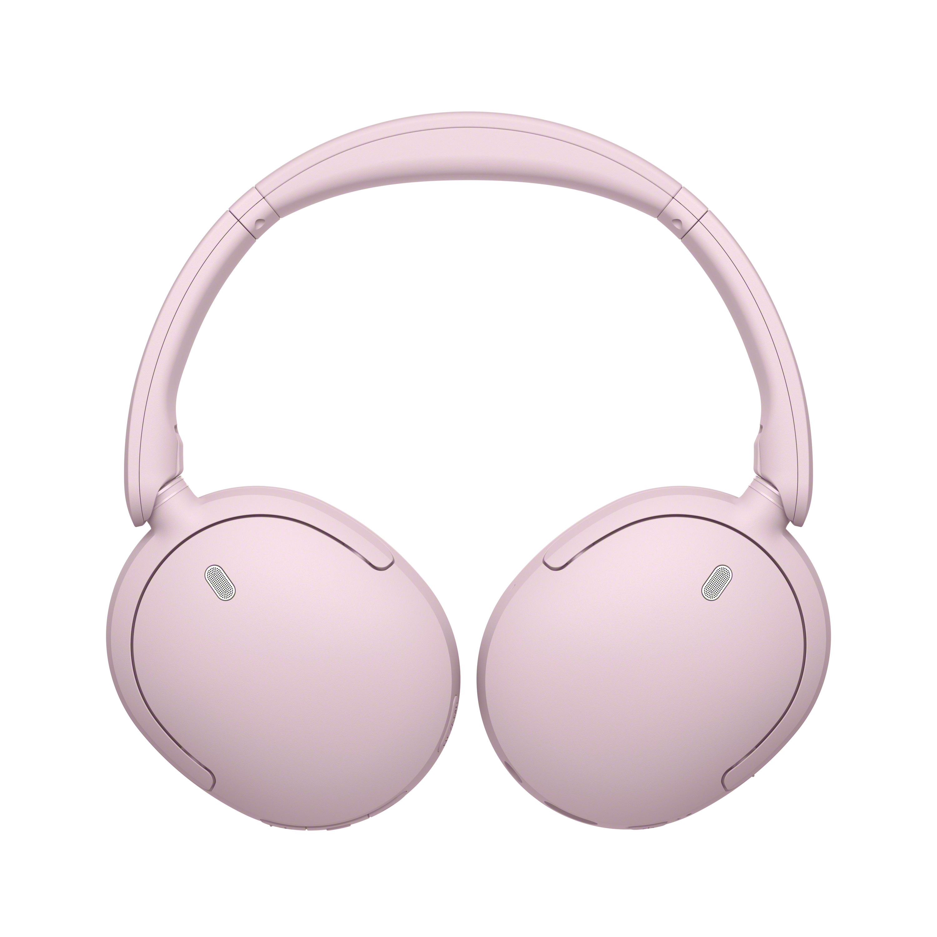 Une paire de casques sans fil modernes circum-auriculaires rose clair sur fond blanc.