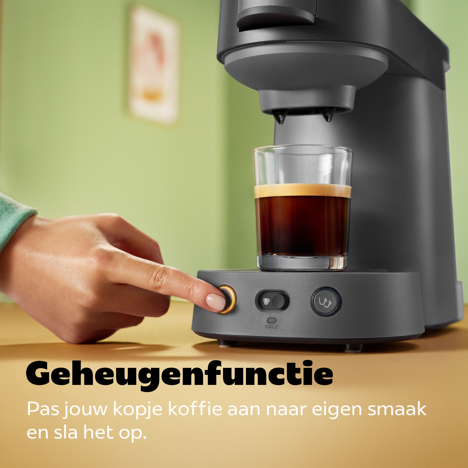 Hand drukt op knop van zwart koffiezetapparaat met gevuld glas.