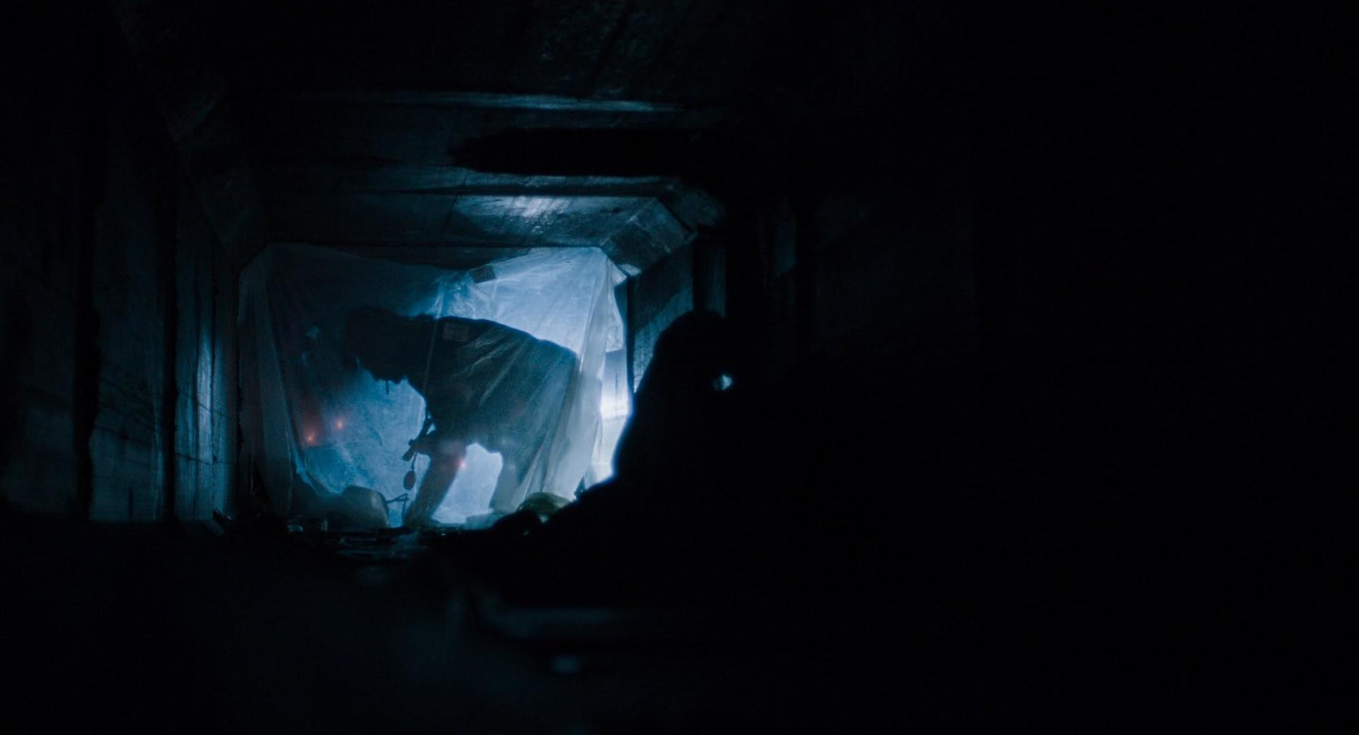 Eine Person im Schutzanzug arbeitet in einem dunklen, beleuchteten Tunnel.