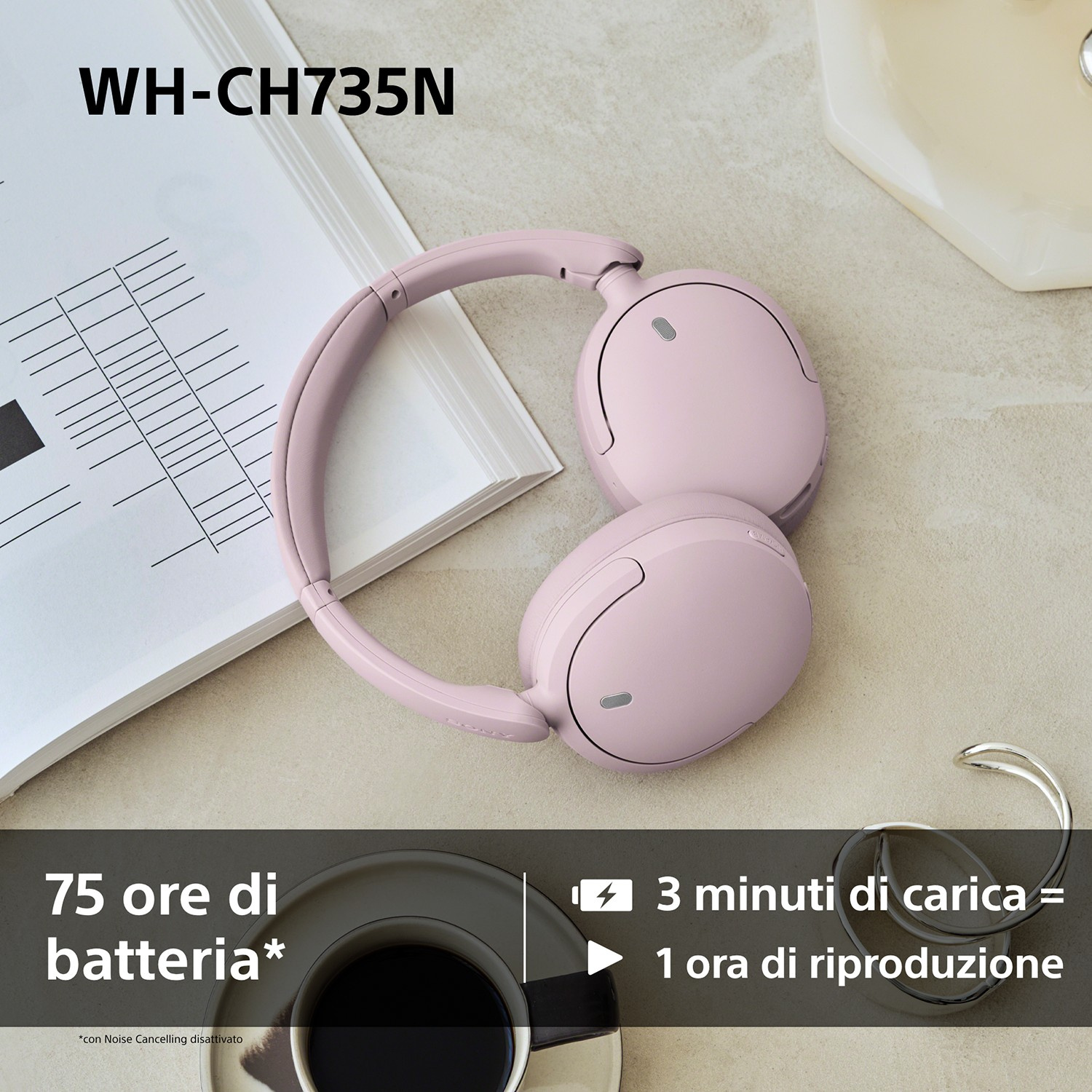Cuffie wireless rosa poggiano su un tavolo accanto a un libro aperto, una tazza di caffe e gioielli.