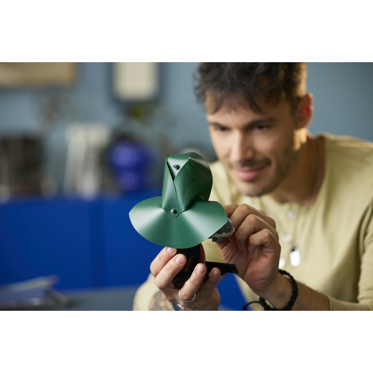 Un giovane tiene in mano un piccolo oggetto verde e lo guarda sorridendo.