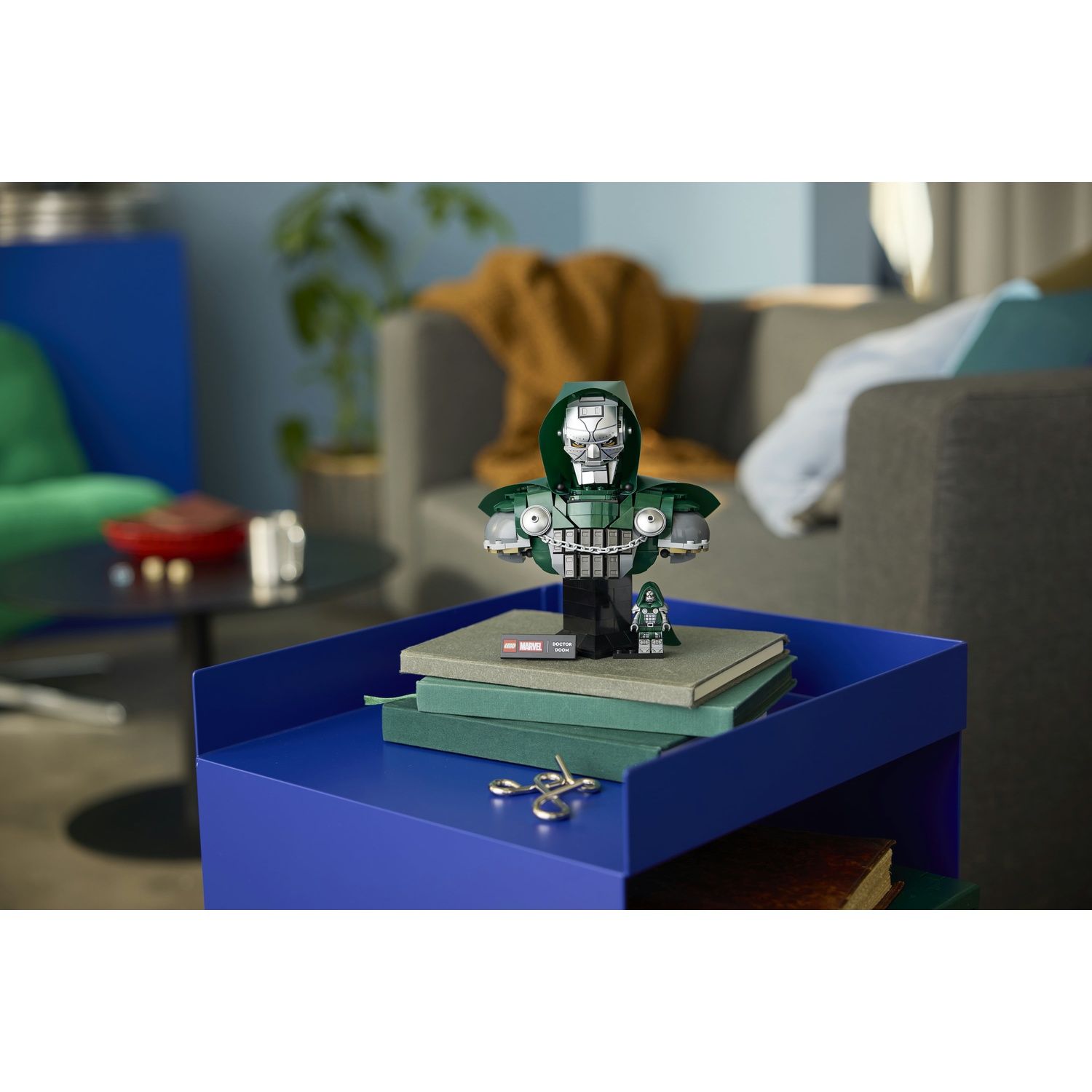 Un busto LEGO del Dottor Destino su libri impilati su un tavolo blu in un soggiorno.