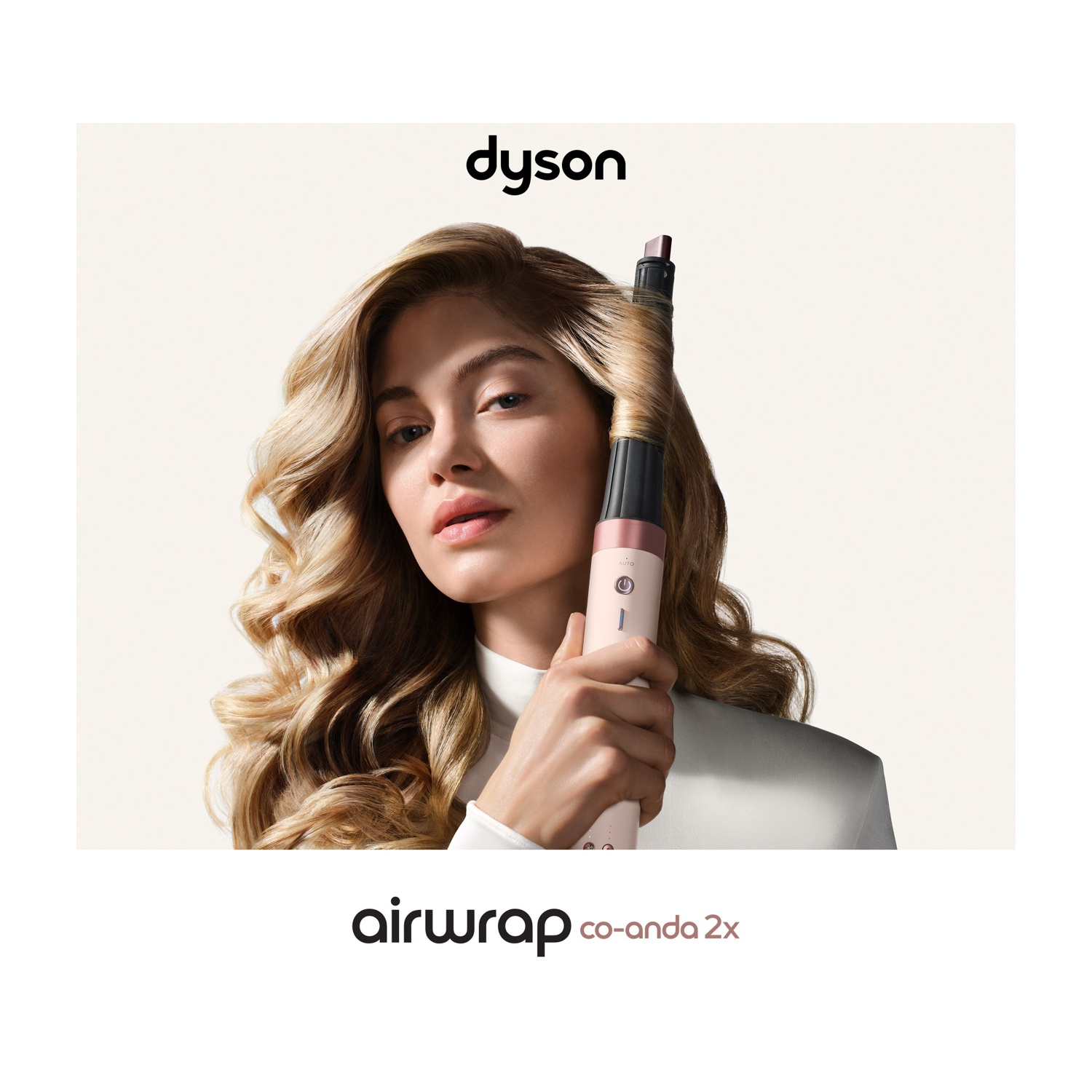 Donna con capelli biondi che modella i ricci usando un Dyson Airwrap.