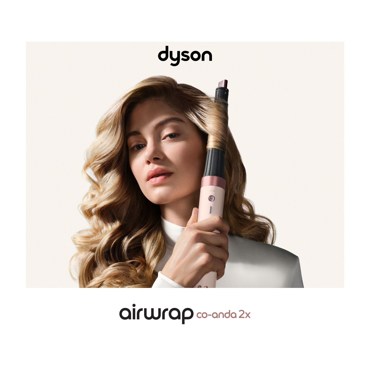 Donna che acconcia capelli biondi con Dyson Airwrap, con logo e testo Dyson in alto e in basso.