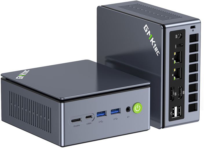 Két szürke GMKtec mini PC elülső csatlakozókkal és világító zöld bekapcsológombbal fehér háttér előtt.
