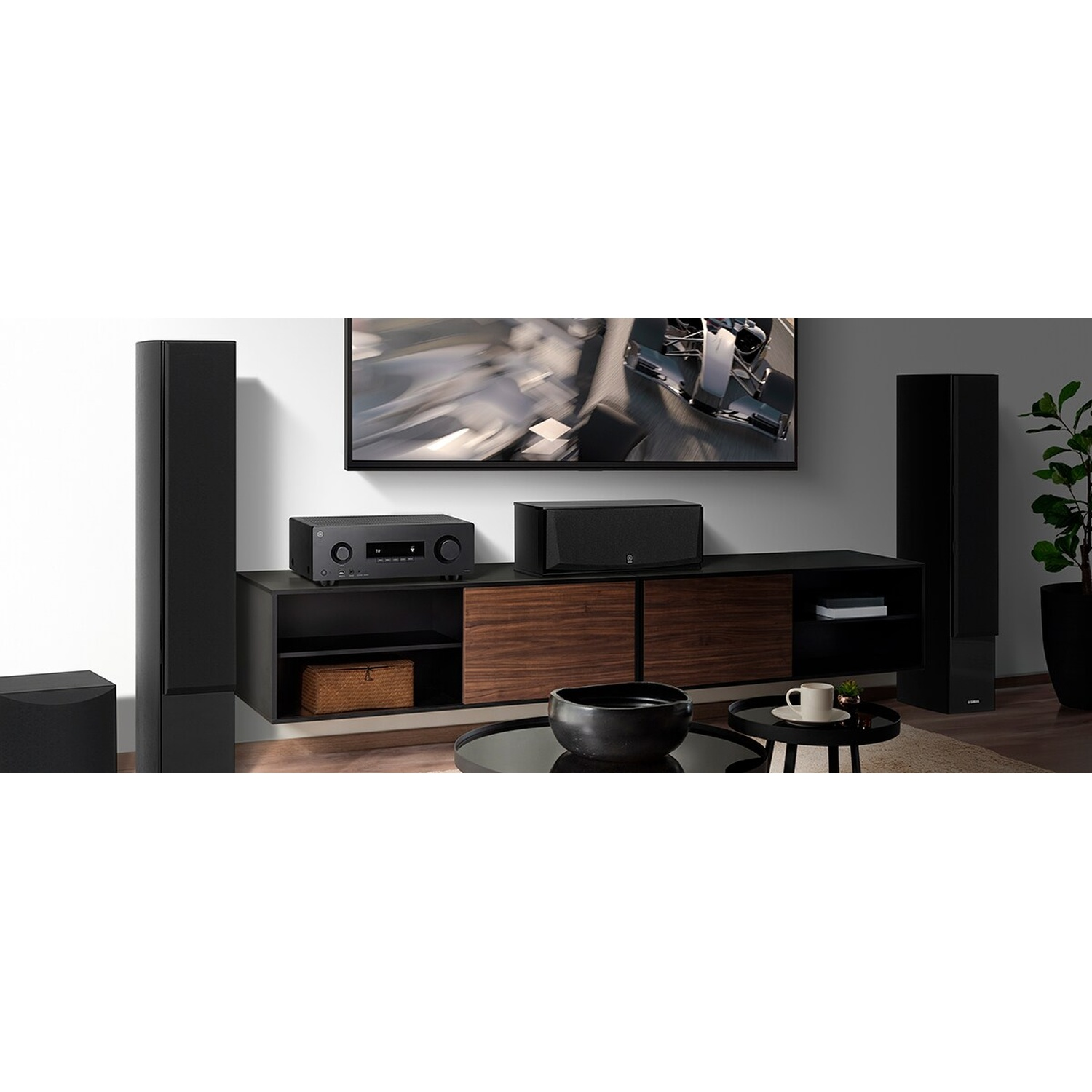 Un soggiorno con TV, impianto audio, altoparlanti neri, console in legno e tavolino.