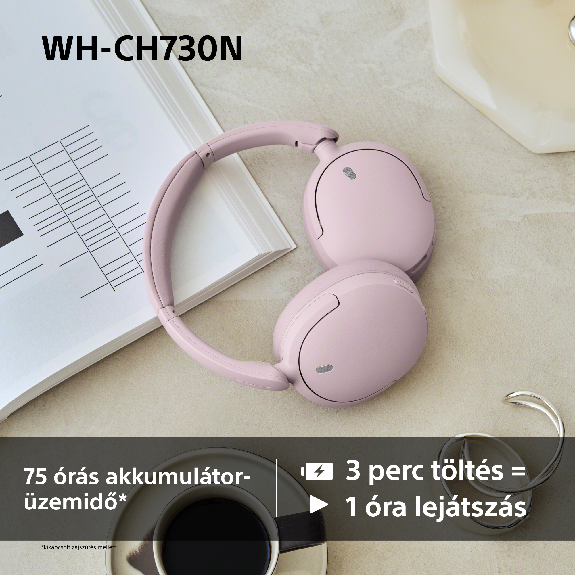 Rozsaszin vezetek nelkuli fejhallgato az asztalon jegyzetek, egy csasze kave es femgyuruk mellett.
