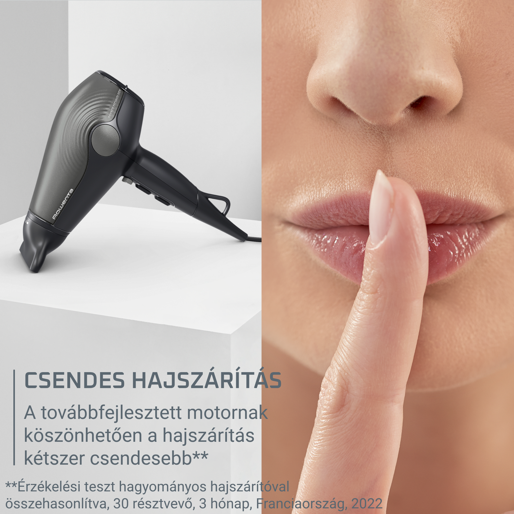 Egy sötétszürke hajszárító fehér állványon egy nő arca mellett, aki az ujját a ajkára teszi.