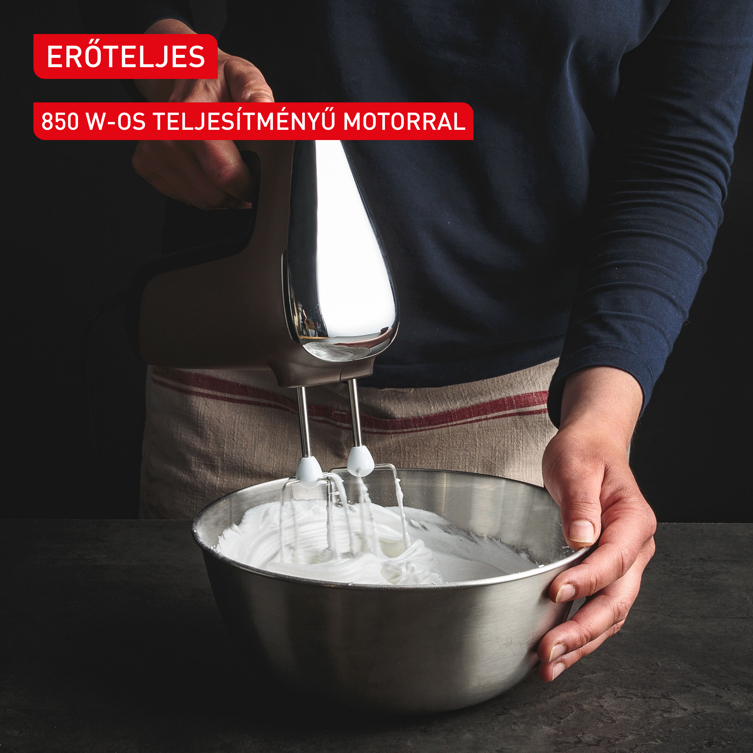 Egy személy barna és króm színű kézi mixerrel tejszínt habosít fel egy rozsdamentes acél tálban.