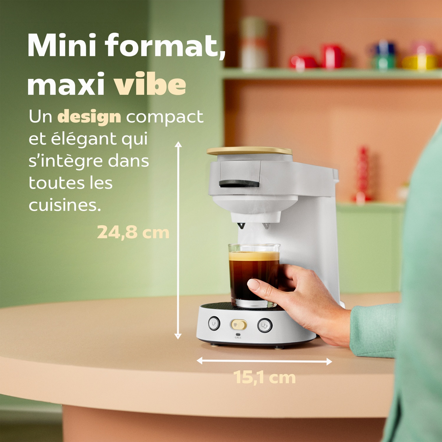 Cafetière blanche compacte avec une tasse en verre sur une table, mesurant 24,8 cm de haut et 15,1 cm de large.