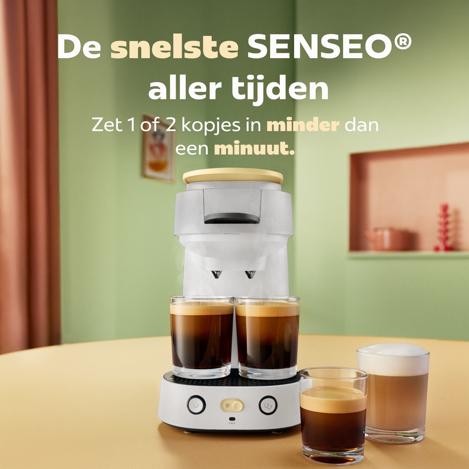 Een witte Senseo koffiezetapparaat op een houten tafel zet twee kopjes koffie. Nederlandse tekst op de achtergrond.
