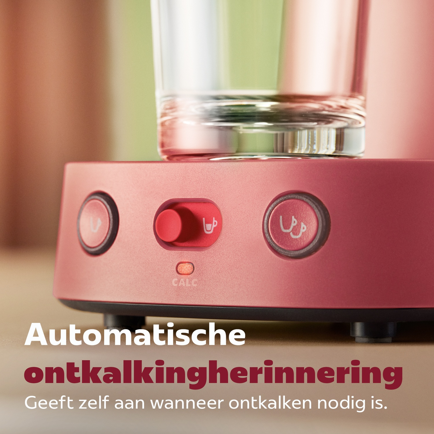 Rode koffiemachine met knoppen en een helder glas bovenop, tekst onderaan.