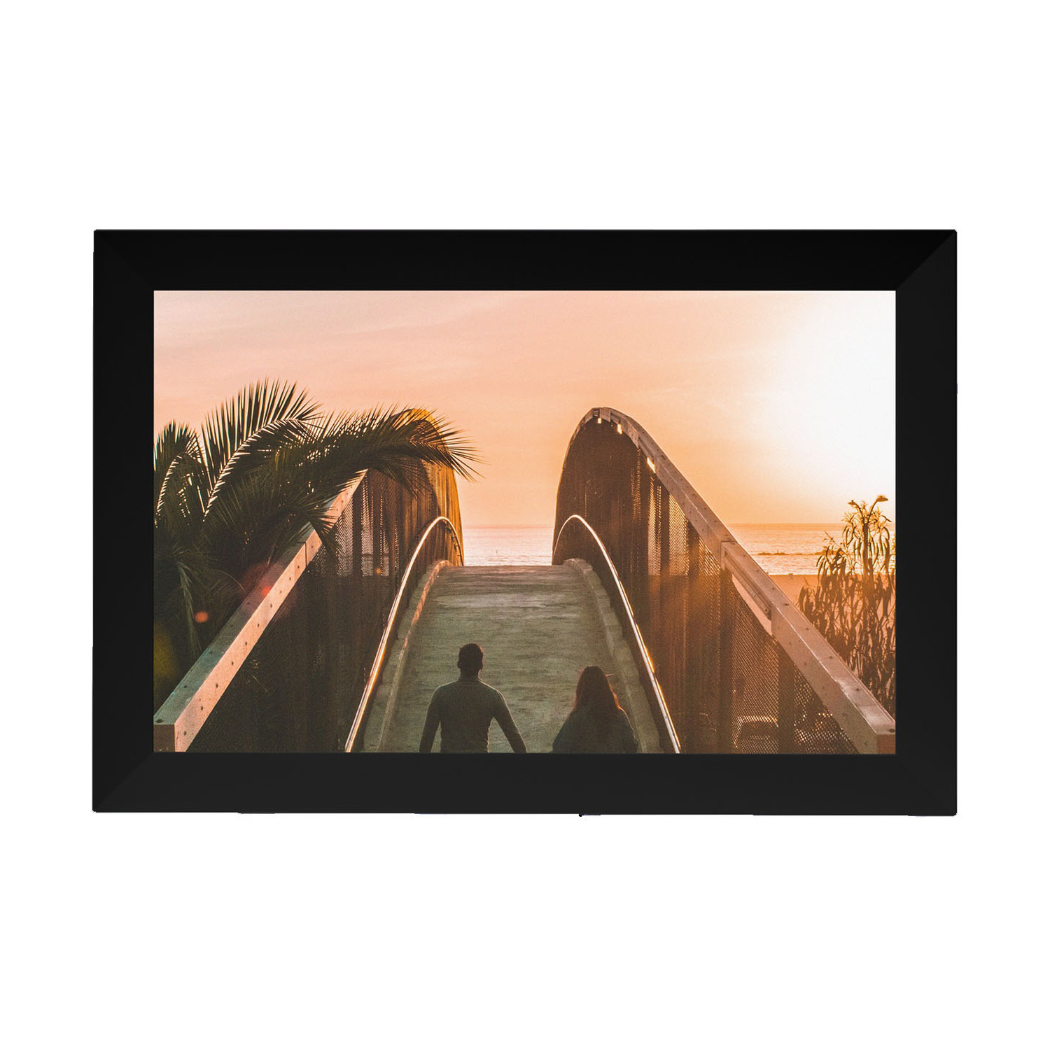 Una coppia attraversa un ponte verso il mare al tramonto, incorniciata da palme.
