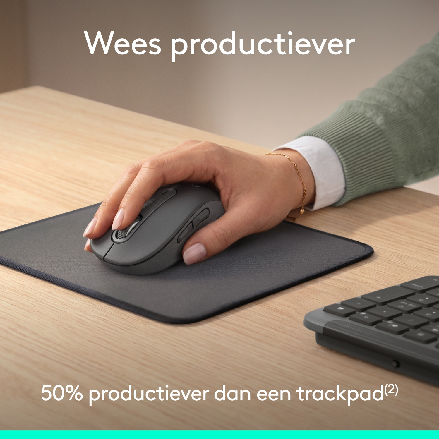 Main utilisant une souris grise sur un tapis près d'un clavier en bois.