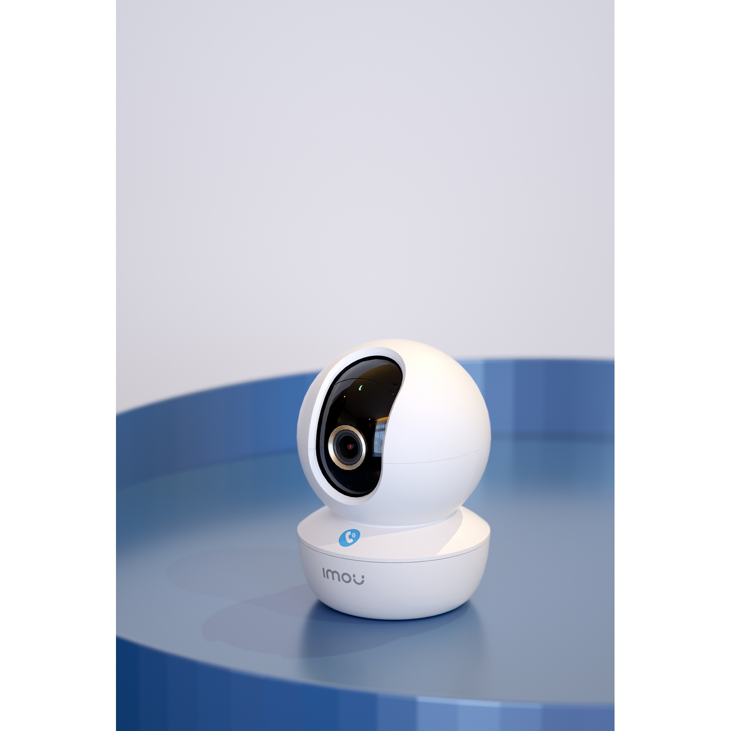 Une caméra de sécurité sans fil blanche est posée sur une table bleue devant un fond blanc.