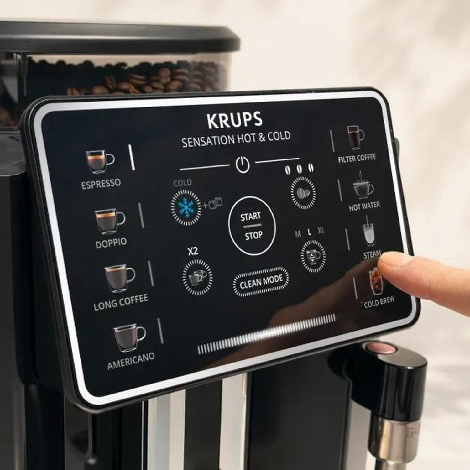 Un doigt appuyant sur l'écran tactile d'une machine à café noire Krups Sensation Hot & Cold.