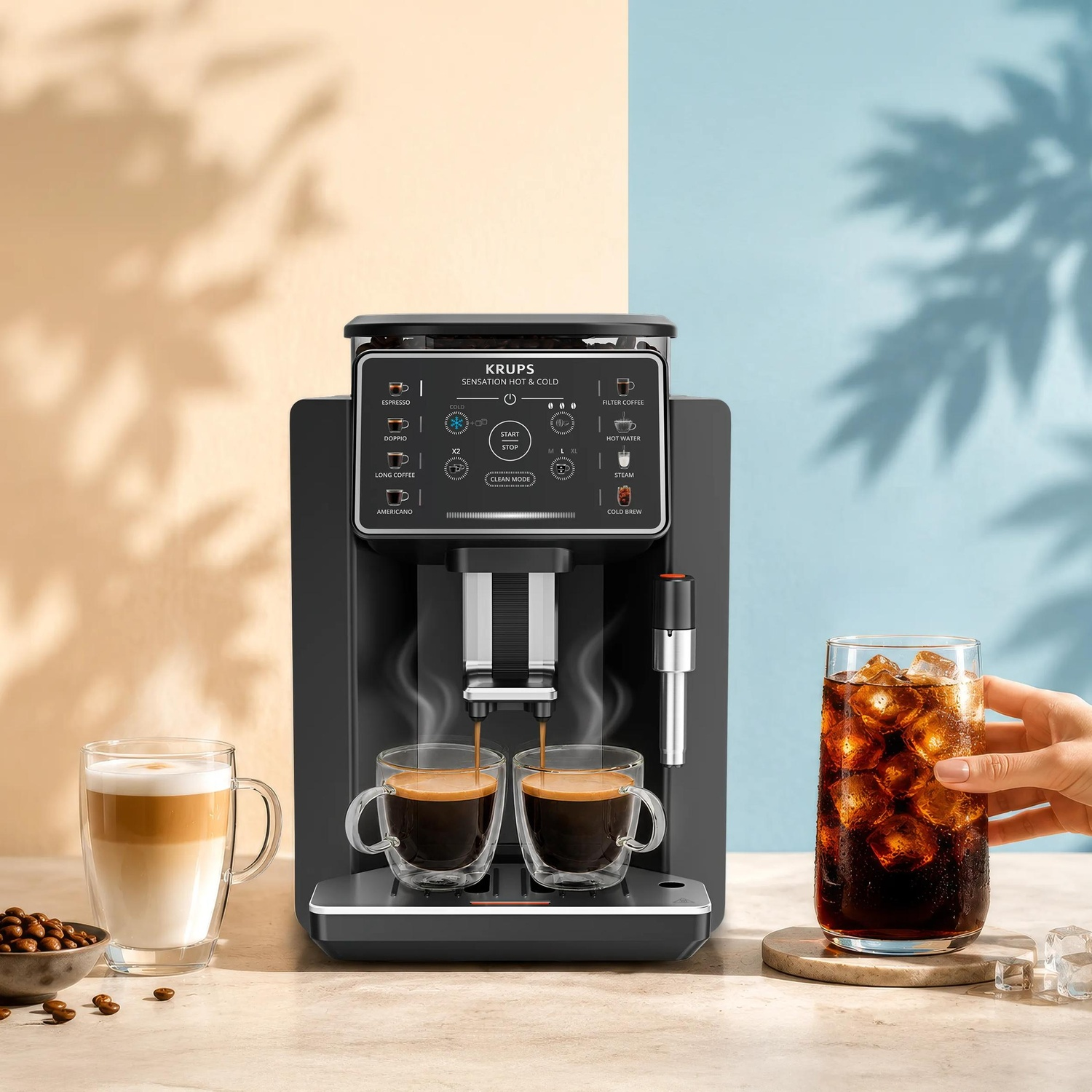 Machine à café Krups noire préparant deux tasses fumantes d'espresso, avec cappuccino, grains et café glacé.