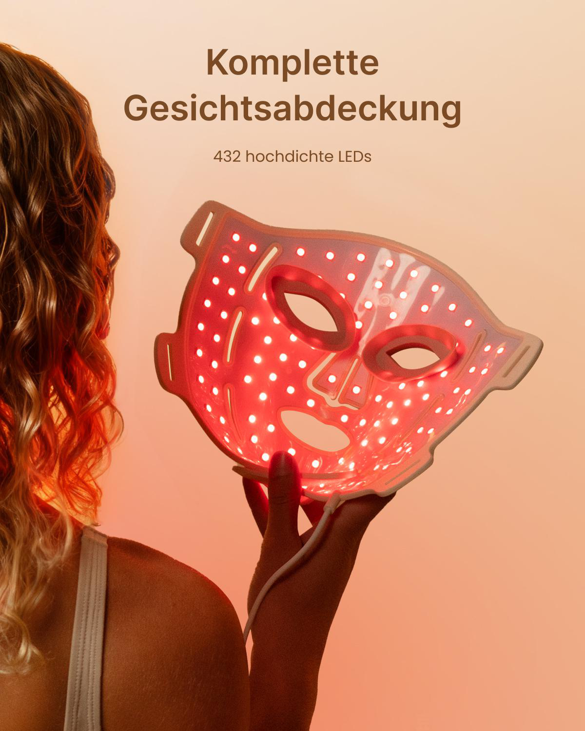 Eine Frau hält eine rote LED-Gesichtsmaske mit vielen kleinen Leuchtpunkten und Text darüber.