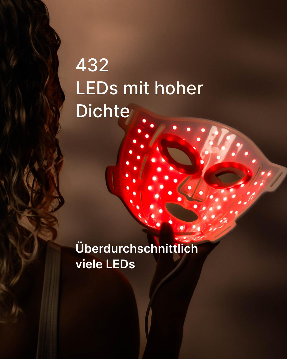 Frau hält eine rote LED-Gesichtsmaske mit vielen leuchtenden Punkten.