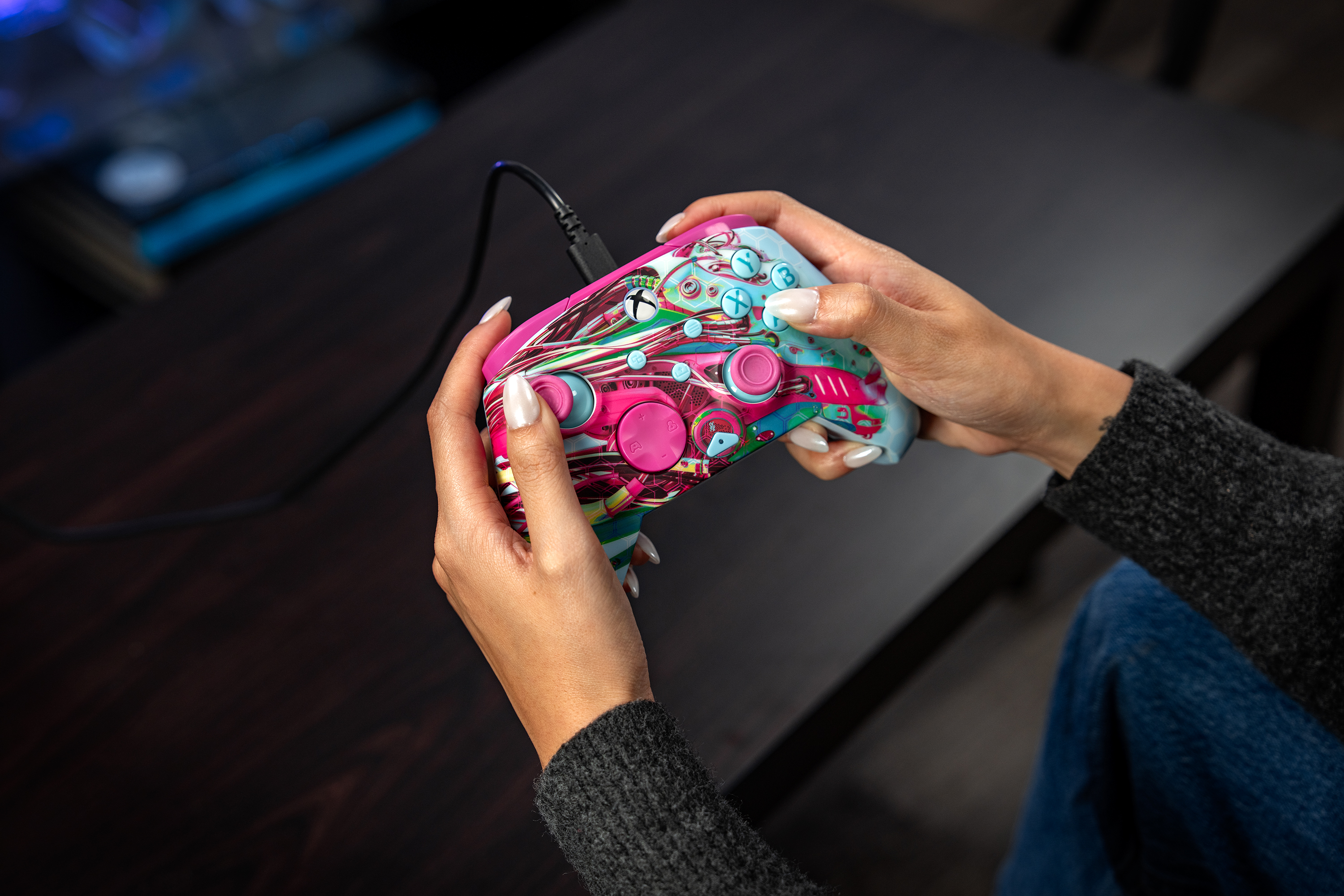 Personne tenant une manette colorée avec fil dans ses mains.
