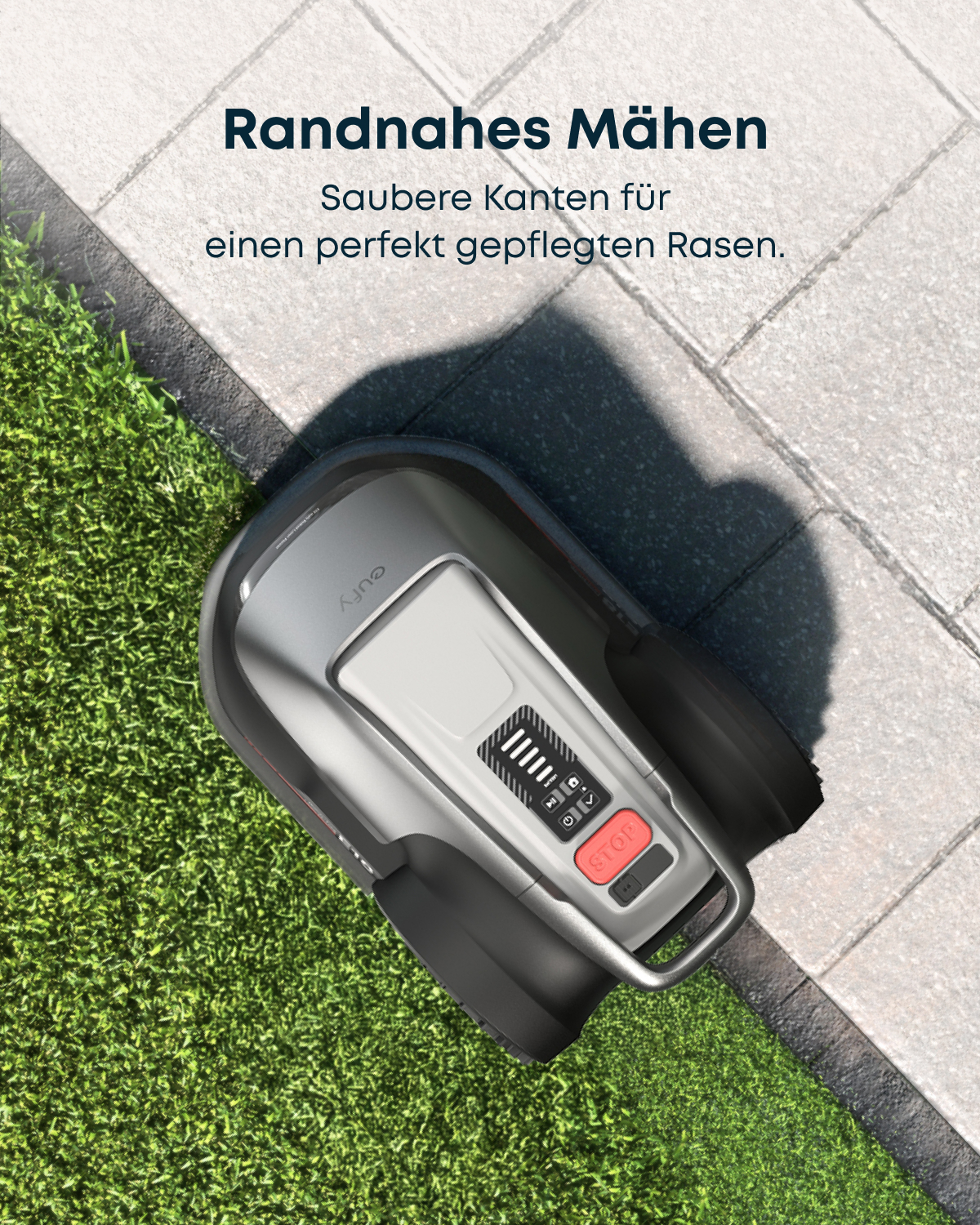 Ein grauer Mähroboter schneidet präzise die Kanten zwischen Rasen und gepflastertem Weg.
