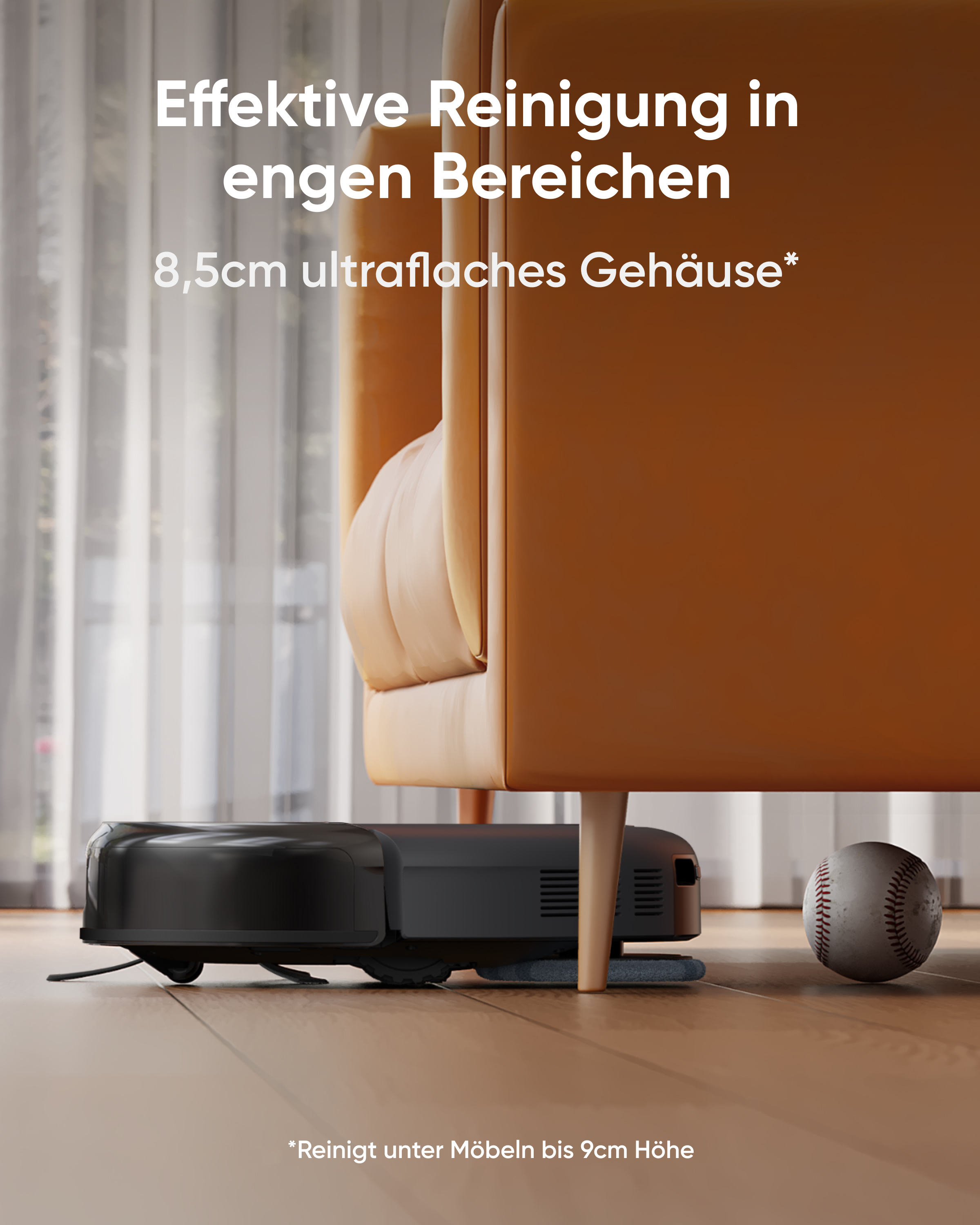 Ein flacher schwarzer Saugroboter reinigt unter einem orangefarbenen Sofa, neben einem Baseball auf dem Holzboden.