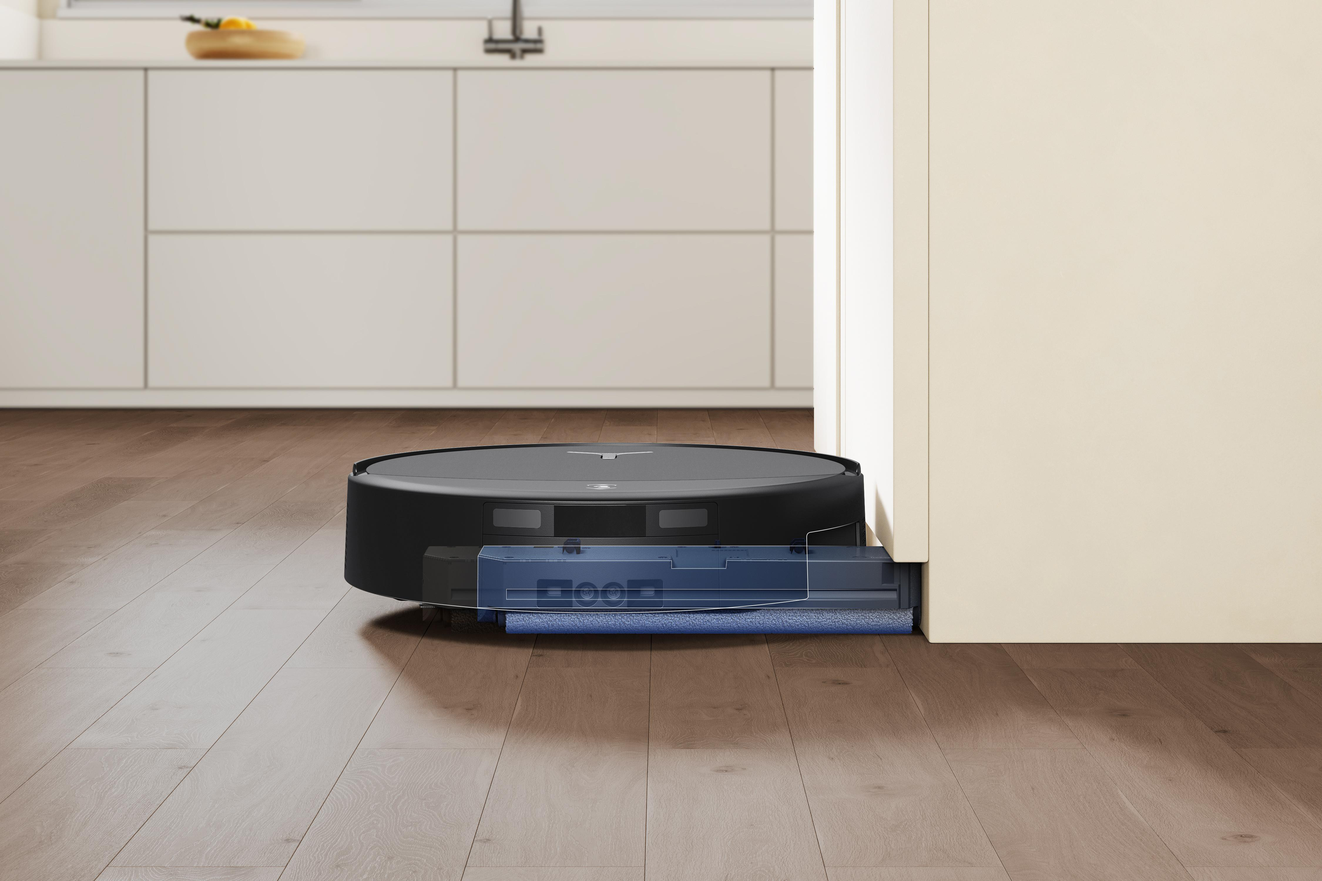 Ein schwarzer Staubsaugerroboter mit ausfahrbarem Wischmopp reinigt einen hölzernen Küchenboden.