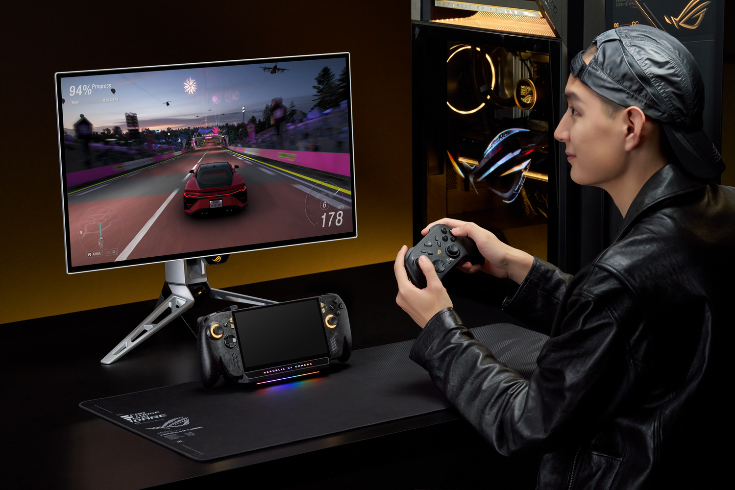 Un joven con chaqueta de cuero juega a un juego de carreras con un mando frente a un monitor.