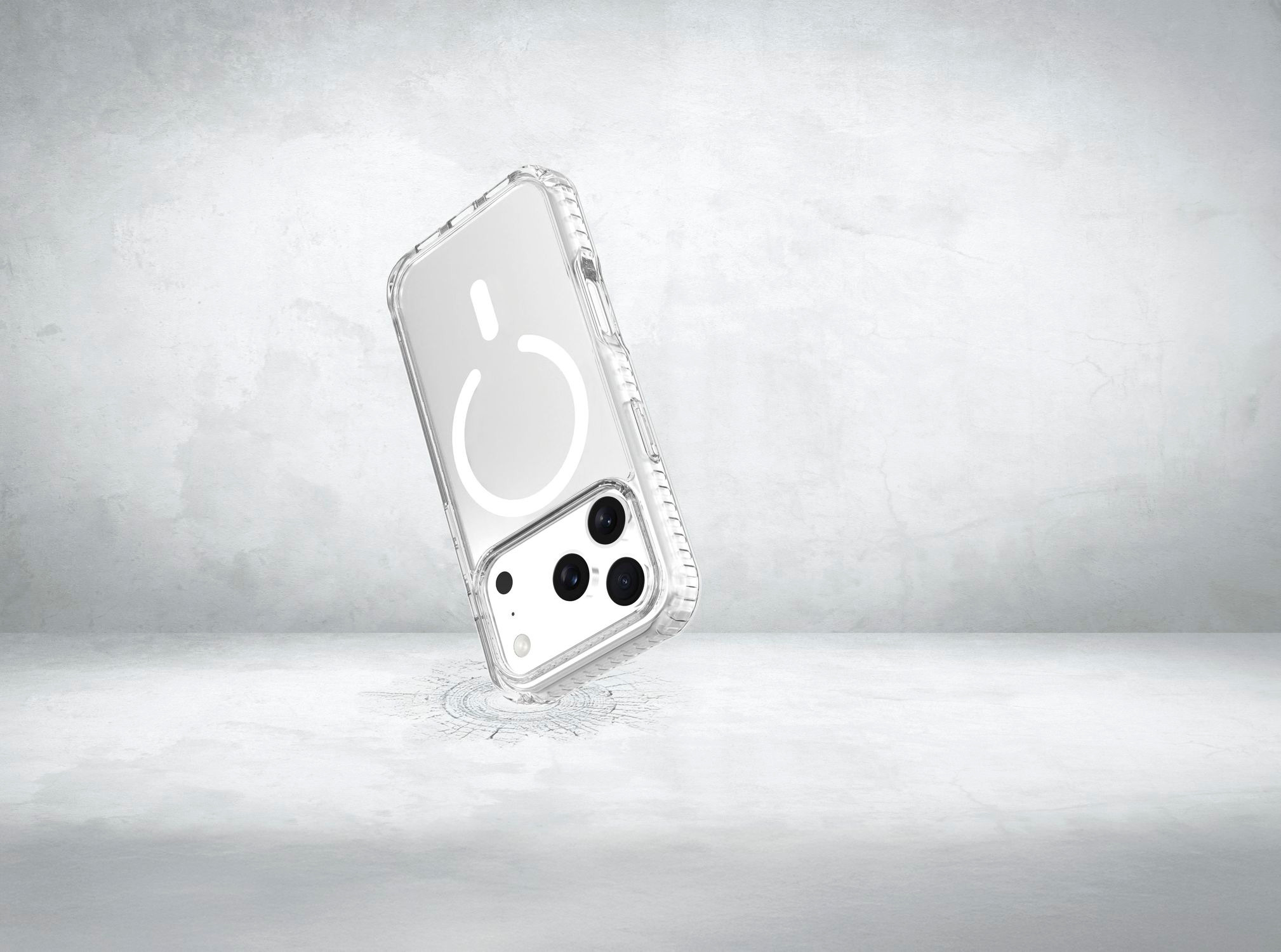 Un teléfono inteligente en una funda protectora transparente flota frente a una pared de hormigón gris.
