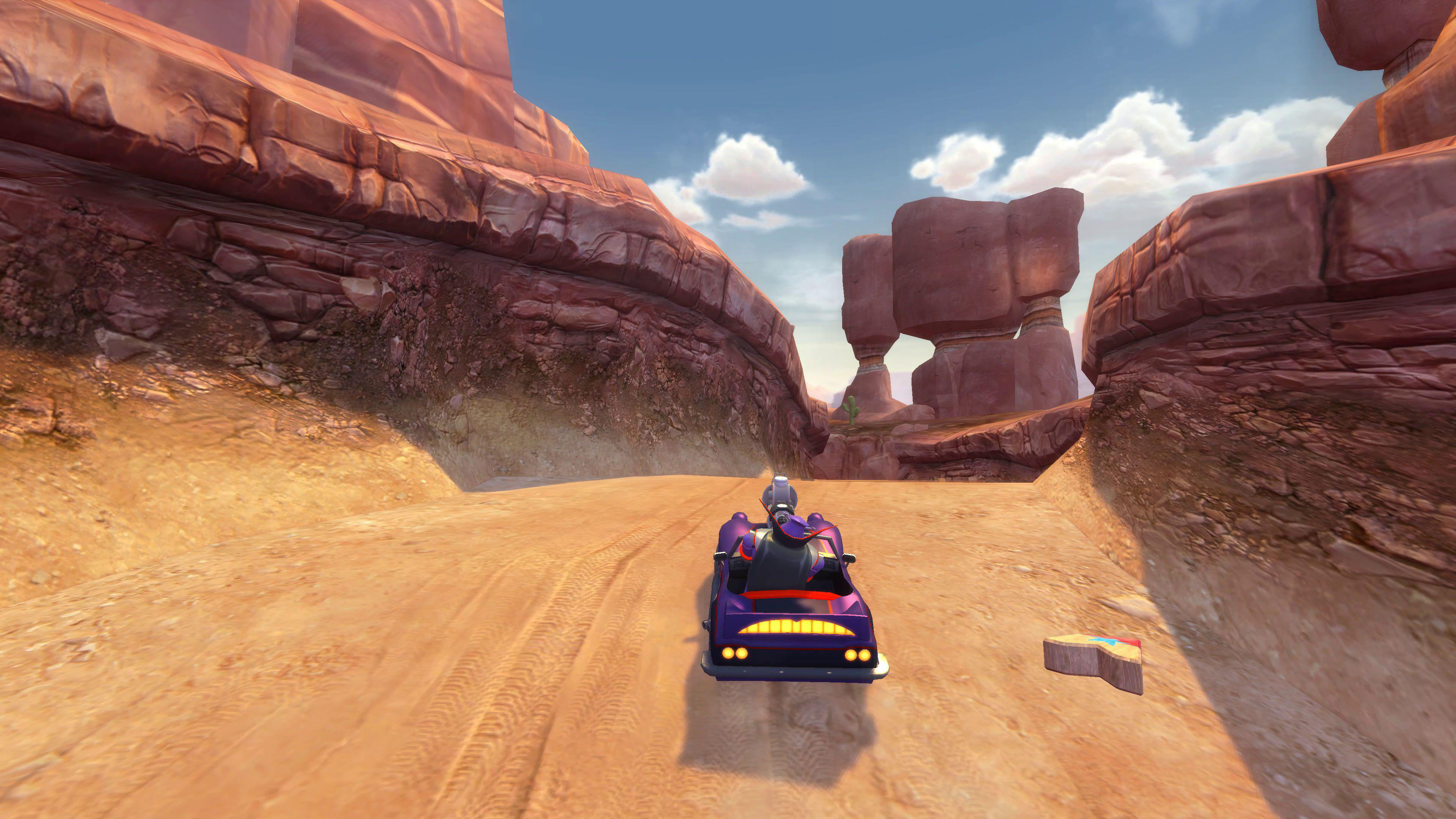 Ein lila Kart fährt durch eine Canyon-Landschaft mit roten Felsen unter blauem Himmel.