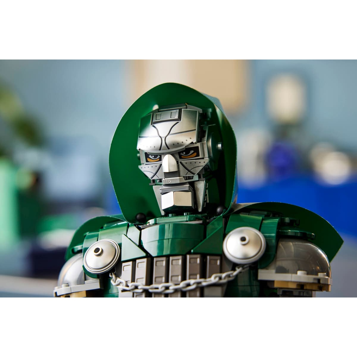 Gros plan d'une figurine Lego du Docteur Fatalis avec cape verte et masque en métal.