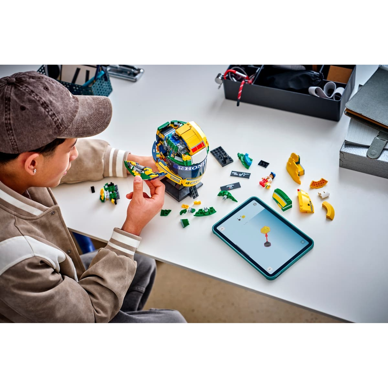 Un garçon construit un modèle Lego coloré à un bureau avec une tablette.
